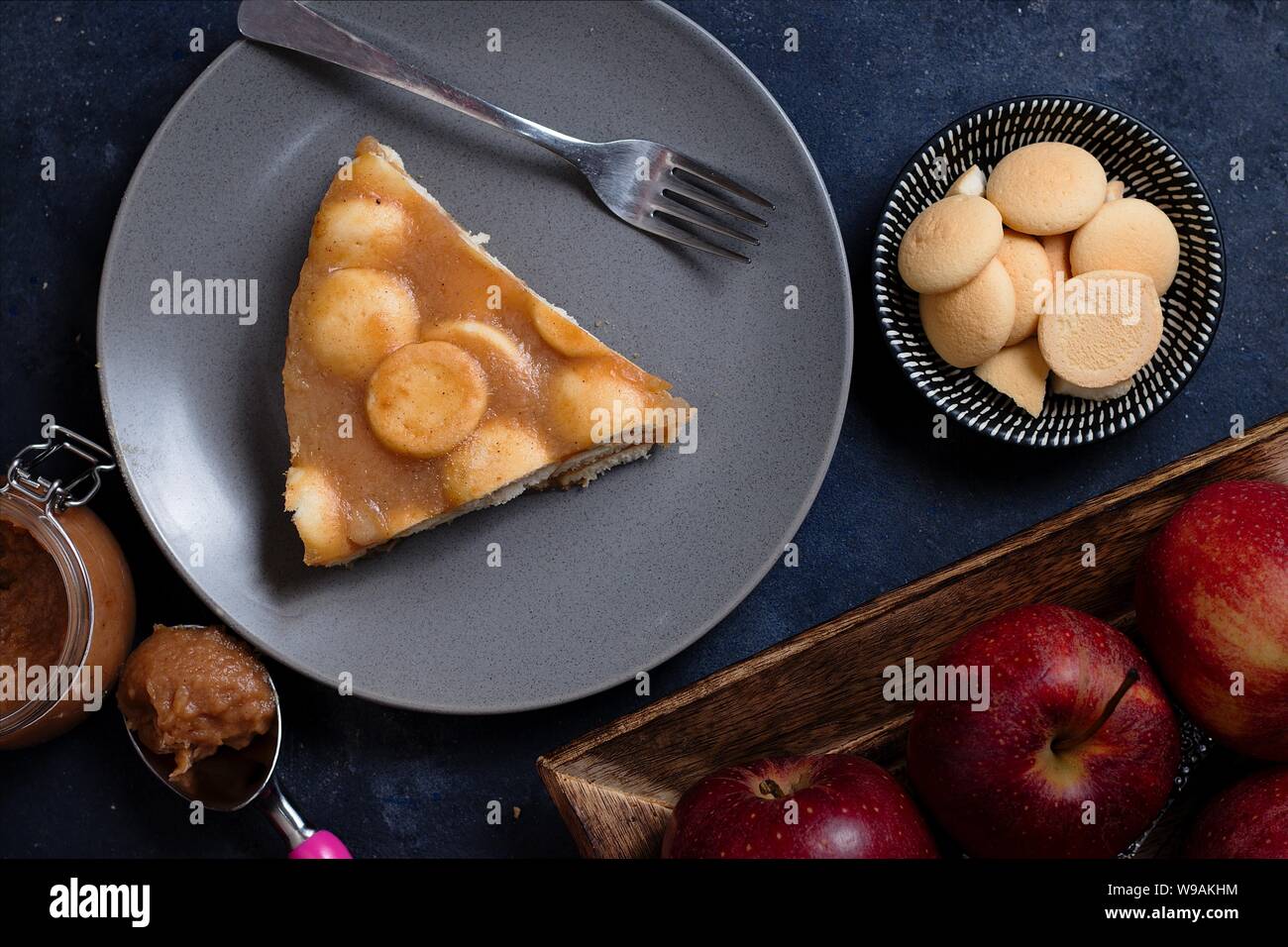 Apfelmus Kuchen mit ladyfinger Gebäck aus direkt über Auf dunkelgrauem Hintergrund mit Gabel, Äpfel, Glas Apfelmus und Schüssel von zusätzlichen biscui Stockfoto