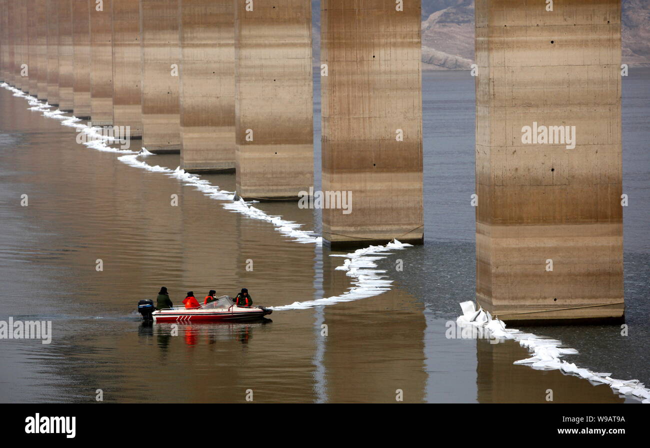 Die chinesischen Arbeiter die eine Barriere mit ölsperren am Gelben Fluss unter dem Nancun Yellow River Bridge Diesel zu stoppen nach einer Ölpest in Mianchi Stockfoto Die chinesischen Arbeiter die eine Barriere mit ölsperren am Gelben Fluss unter dem Nancun Yellow River Bridge Diesel zu stoppen nach einer Ölpest in Mianchi Stockfoto