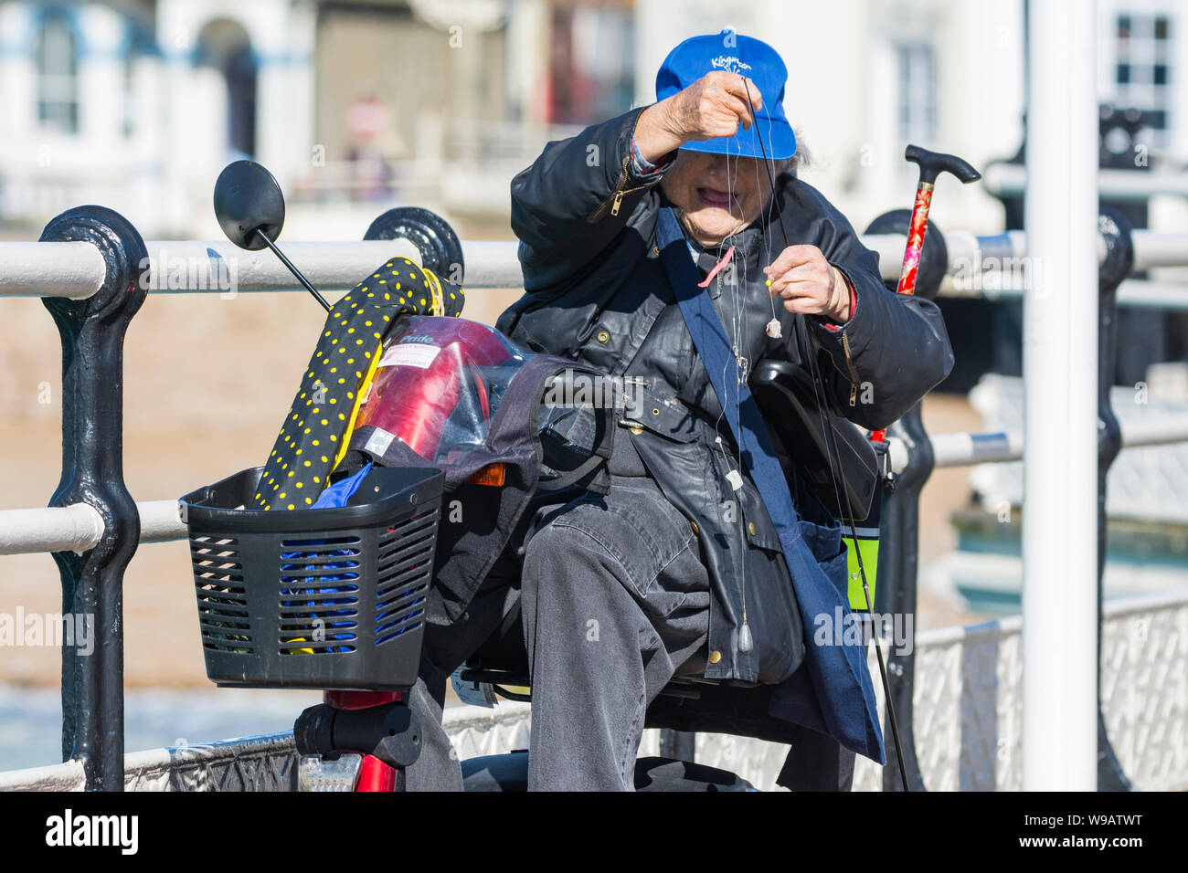 Active Senior behinderte Frau in einem Mobilität scooter Vorbereitung einer Angelschnur. Stockfoto