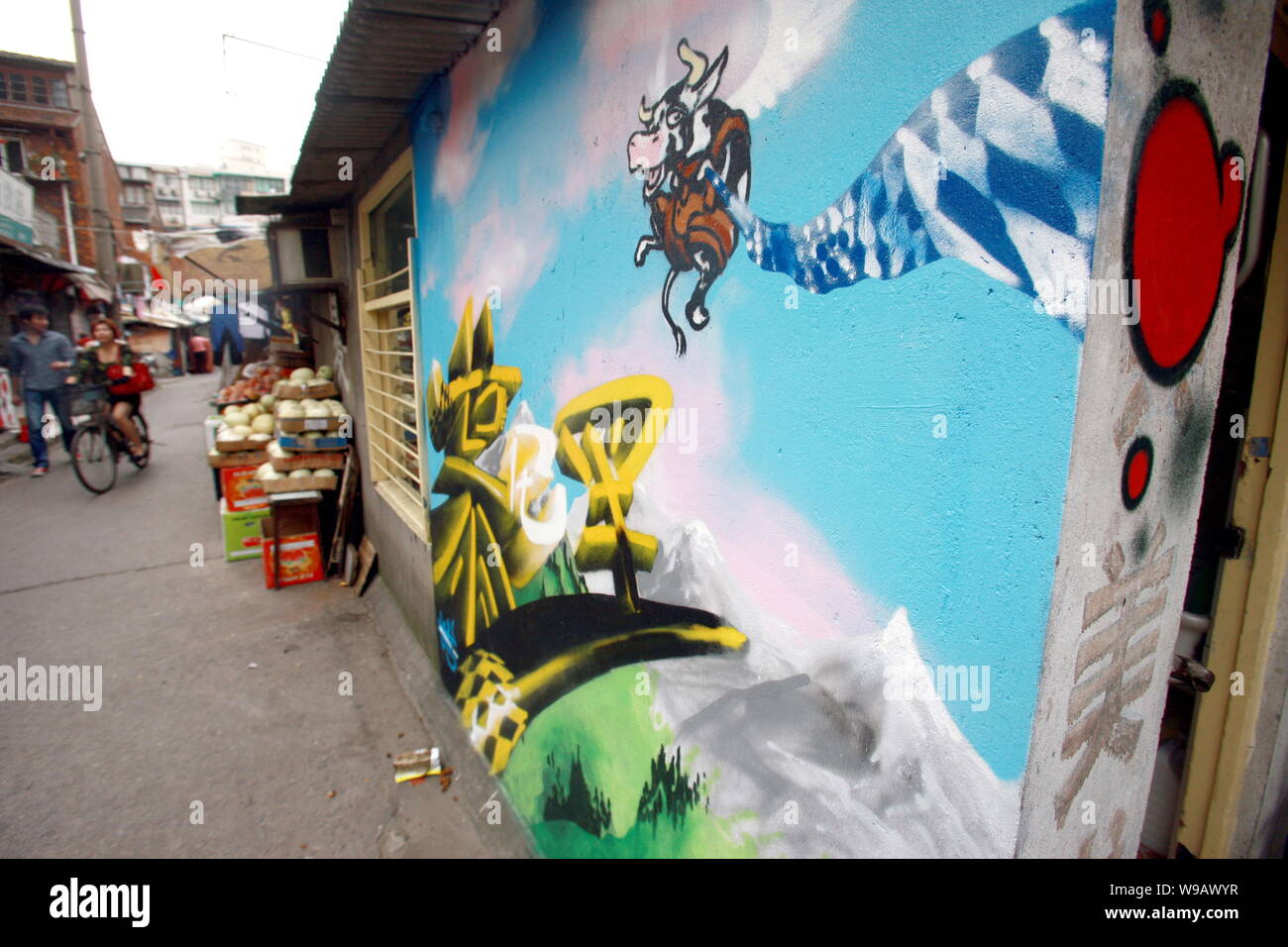 Lokale chinesische Bewohner Pass durch ein Bild an der Wand eines Hauses in der Spur eines Slums in Shanghai, China, 26. Mai 2010. Stockfoto