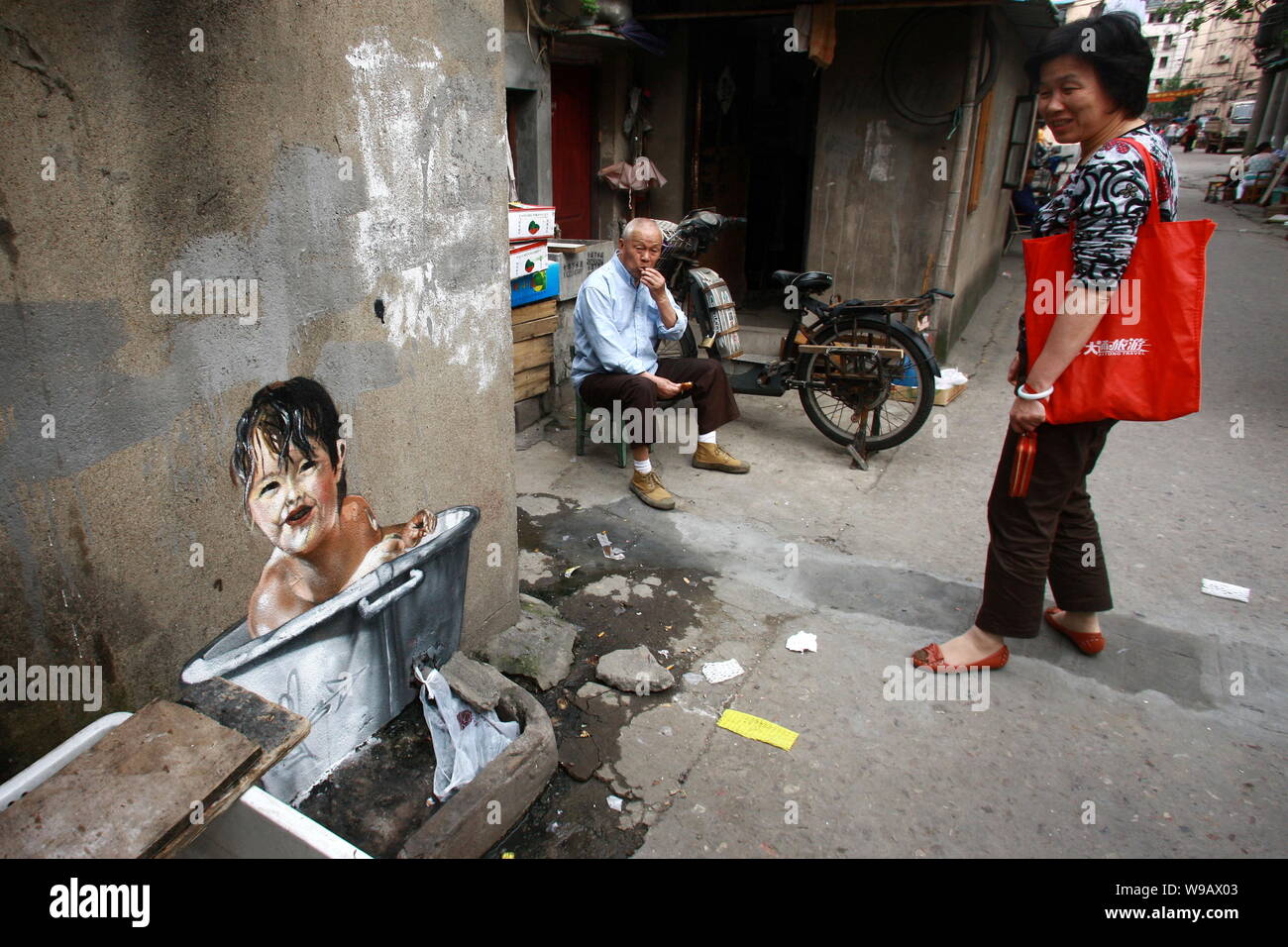 Eine chinesische Bewohner betrachtet ein Bild von einem Kind die Badewanne an die Wand eines Hauses in der Spur eines Slums in Shanghai, China, 26. Mai 2010. Stockfoto