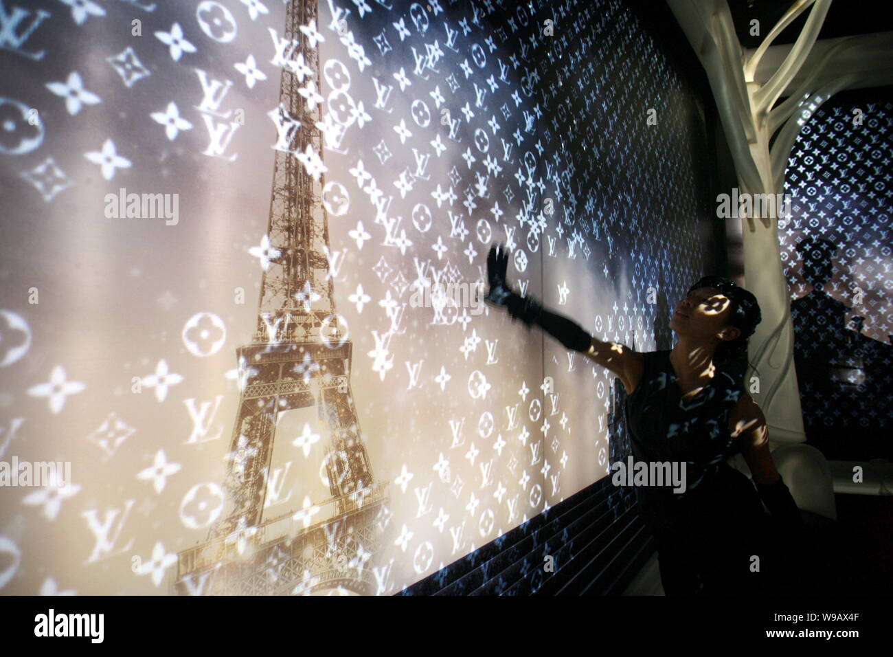 Ein Modell steht vor einer Wand auf, die Louis Vuitton logos während einer  Ausstellung im französischen Pavillon auf der Expo in Shanghai projiziert  werden Stockfotografie - Alamy