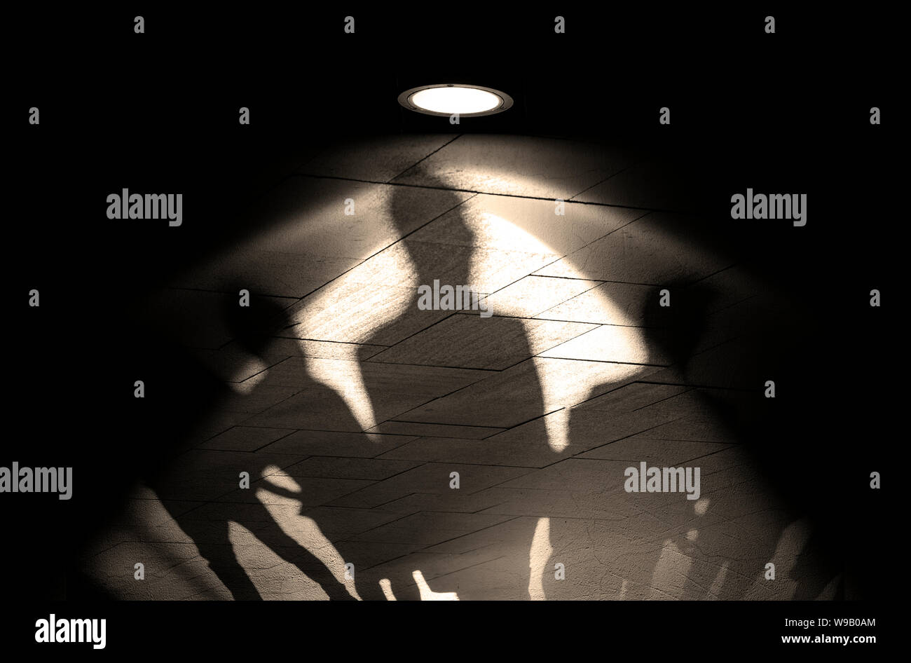Gruppe von Menschen, Silhouetten und Schatten an der Wand, Licht der Lampe oder Flutlicht auf der alten Mauer mit Schatten, Konzept Bild Stockfoto