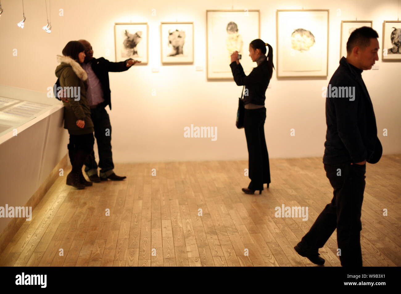 Chinesische artiest Guo Wei, rechts, Spaziergänge Vergangenheit kamerunischen Künstlers Barthelemy Toguo, zweite links, posieren für Fotos mit einem Besucher während der B. Toguo/Guo Stockfoto