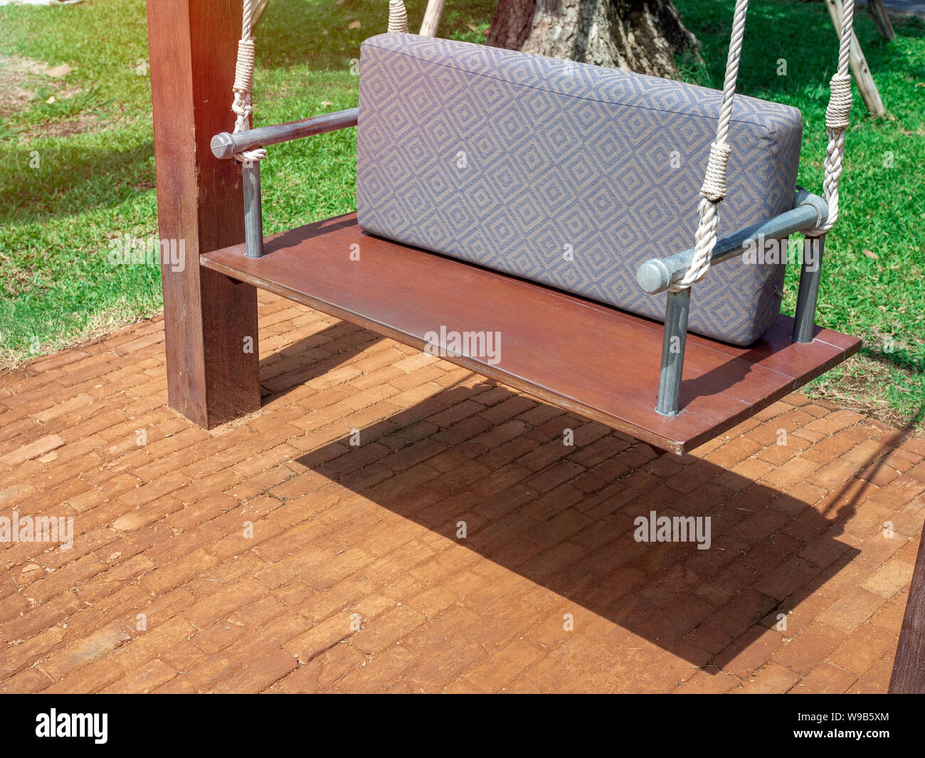 Holz Swing Sitzbank Mit Kissen Auf Backstein Und Grunen Gras Im Garten Stockfotografie Alamy