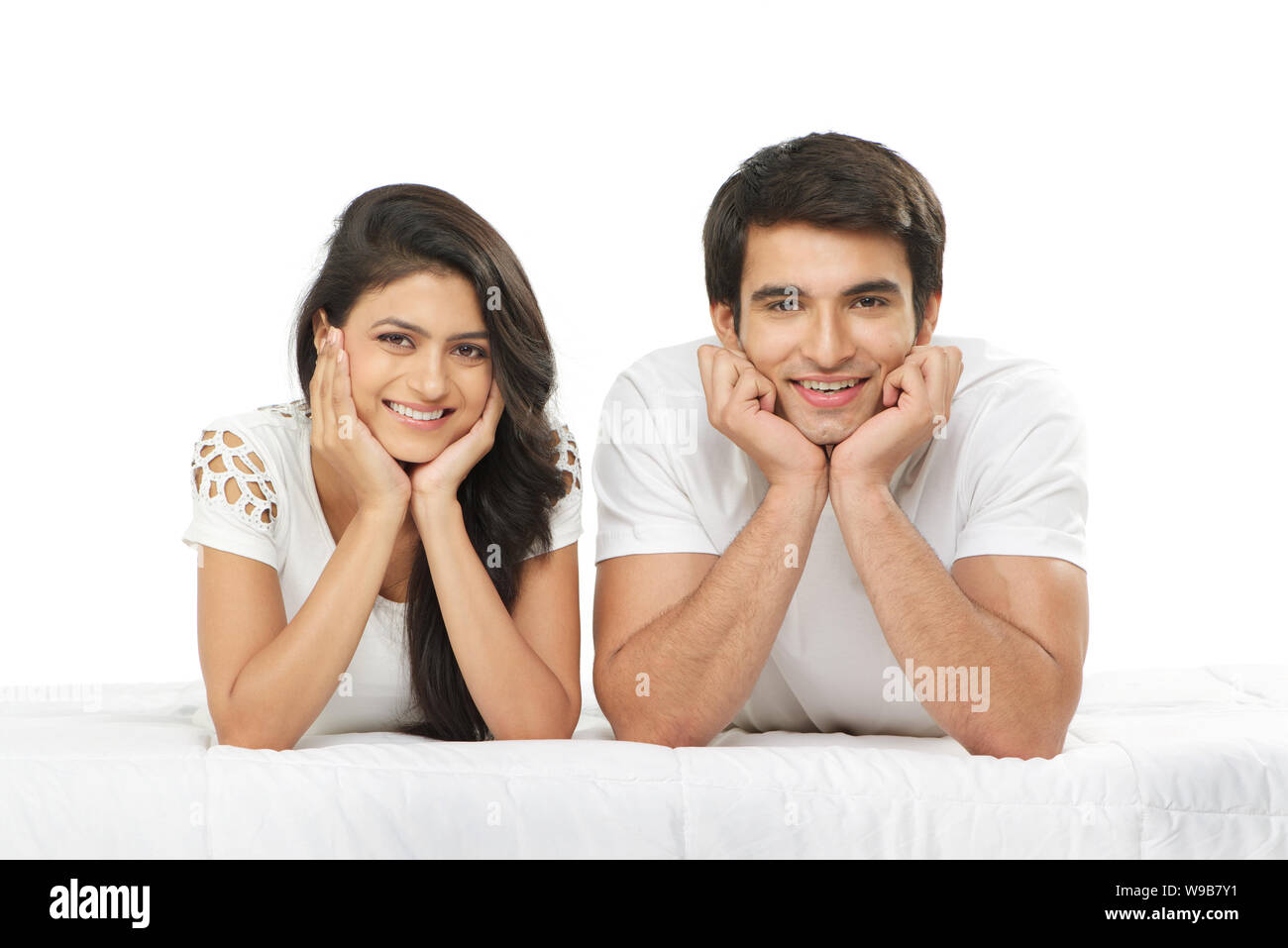 Junges Paar auf dem Bett liegend und lächelnd Stockfoto