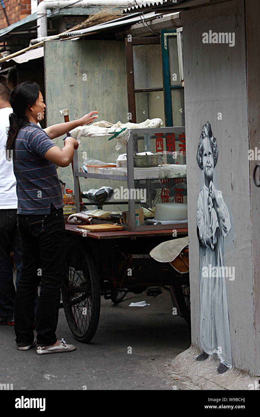 Eine chinesische Street Hersteller Lebensmittel neben einem Gemälde von einem westlichen Mädchen an der Wand eines Hauses in der Spur eines Slums in Shanghai, China, 26 Ma Stockfoto