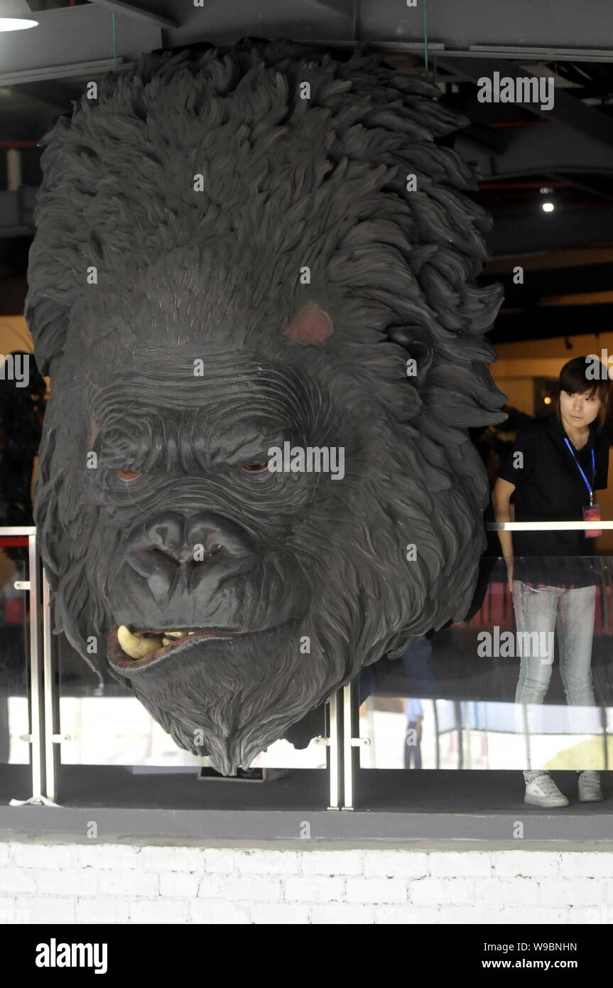 Eine chinesische Frau steht neben einem Modell der King Kong während der Shanghai International Film Prototyp Ausstellung in Shanghai, China, 8. August 2010. Stockfoto