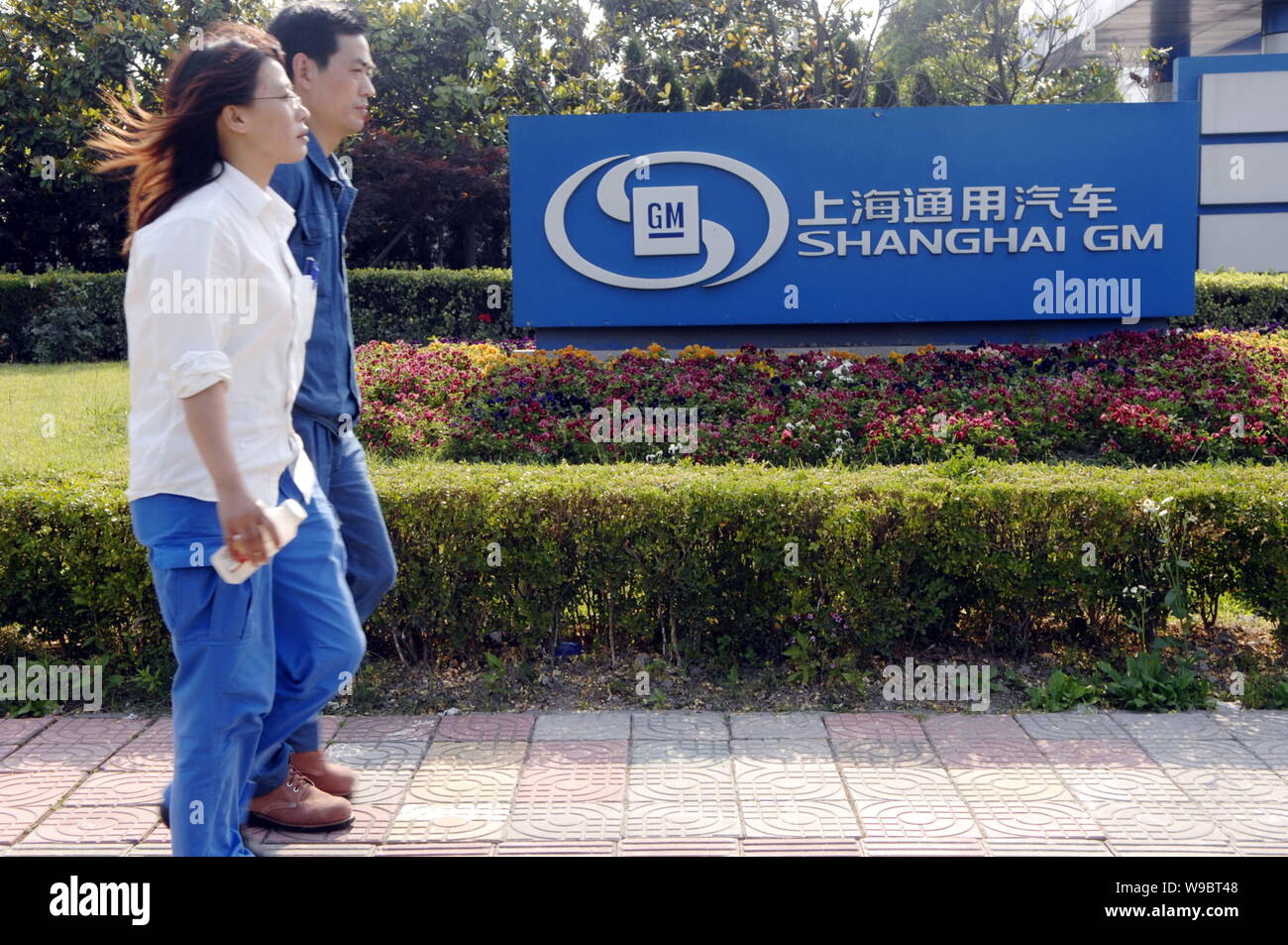 ------ Chinesische Arbeiter vorbei an einer Anlage von Shanghai GM, das Joint Venture zwischen GM (General Motors) und SAIC (Shanghai Automotive Industry Corporation Stockfoto