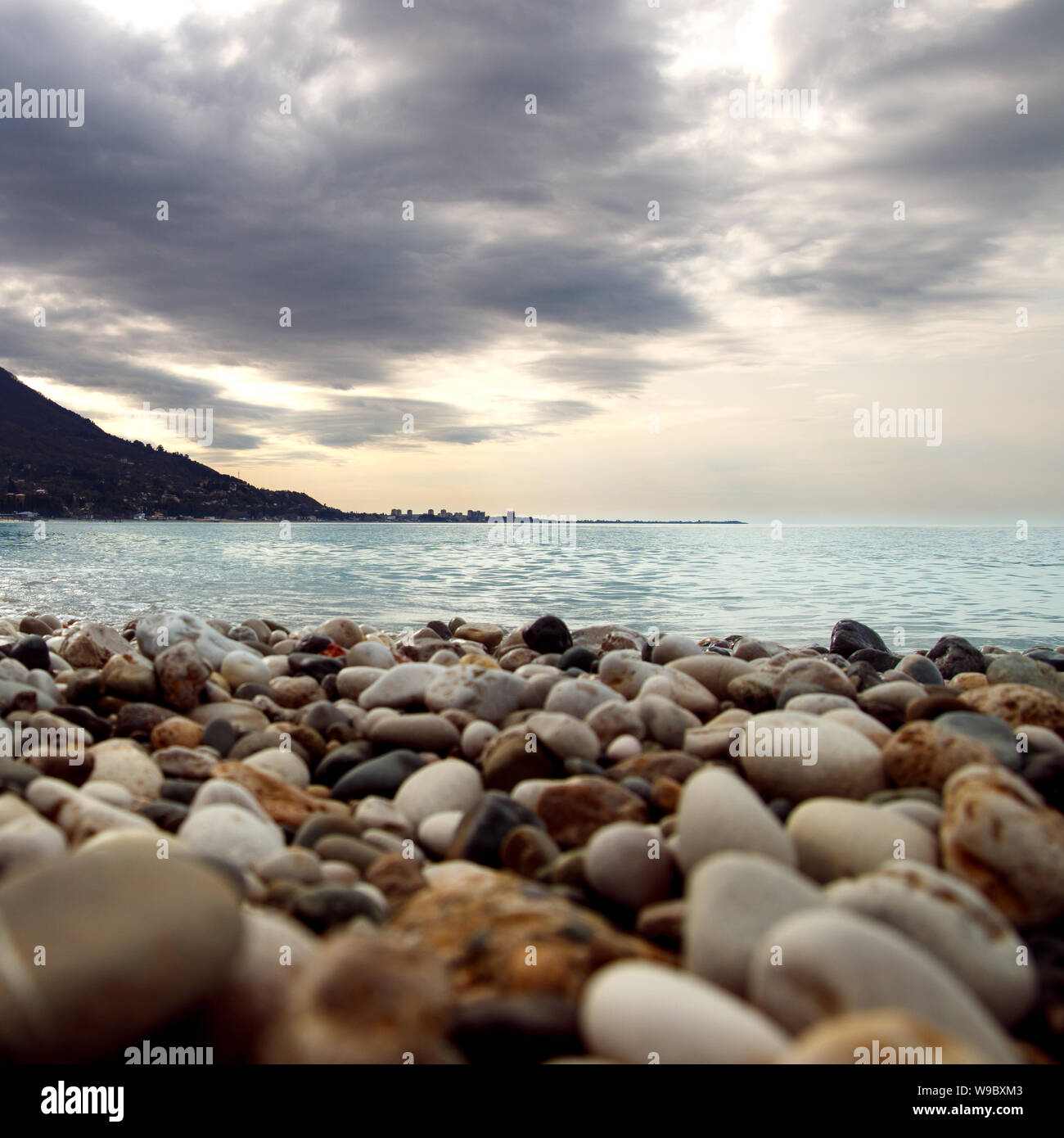 Ruhiges Wasser an der Küste. Welligkeit des Wassers in der Nähe der Küste. Silhouette der Stadt auf die Skyline. Stein Küste vor dem Sturm. Rocky Beach in der Nähe der Bucht. Stockfoto