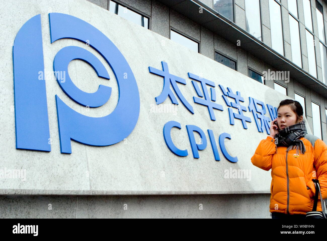 ---- Eine junge chinesische Frau geht vorbei an einer Tafel von CPIC (China Pacific Insurance (Group) Co.) in Shanghai, China, 11. Februar 2008. China Pazif Stockfoto