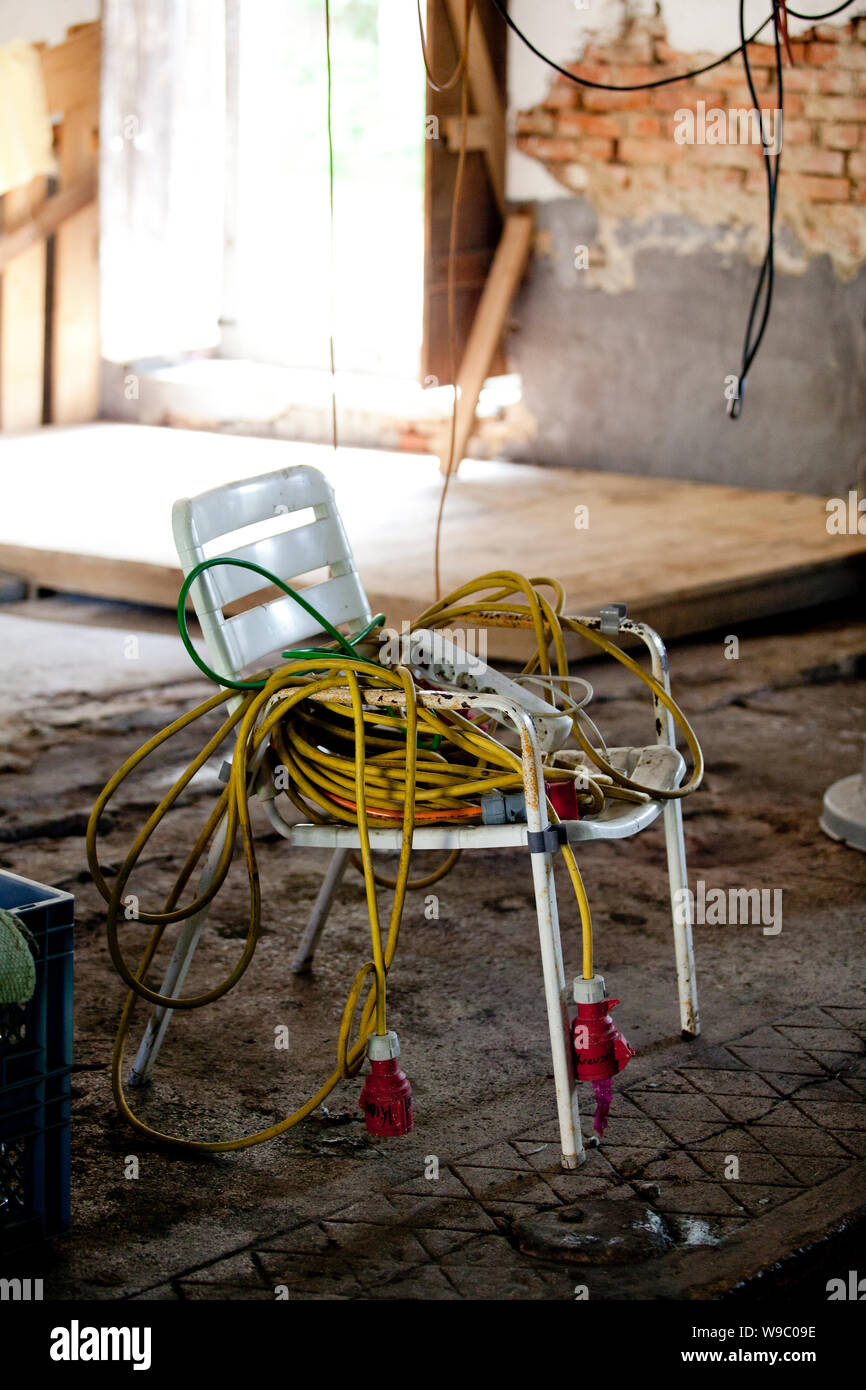 Eine Verwirrung der elektrischen Kabel über einen Vintage Stuhl hängend Stockfoto