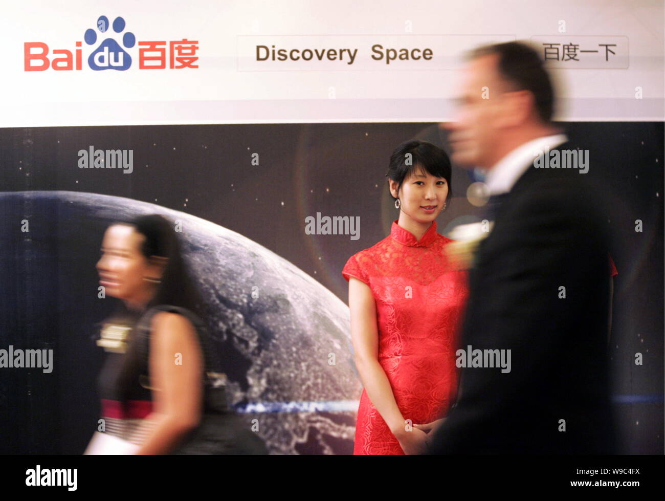 Attendents Spaziergang, vorbei an einem Namensschild für Baidu und die Discovery Channel während einer Pressekonferenz über die strategische Partnerschaft zwischen Baidu und Stockfoto
