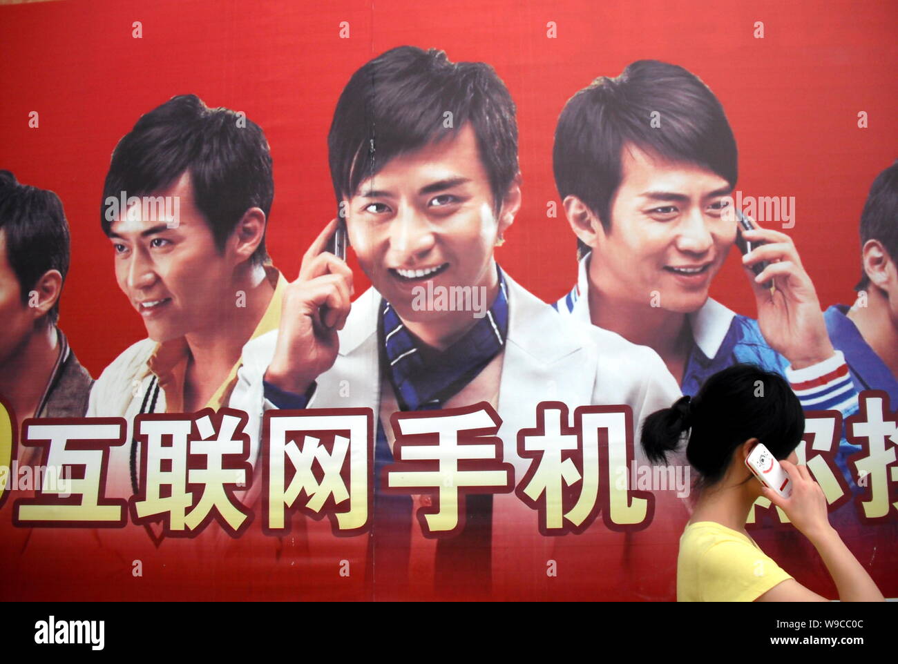 ---- Eine junge chinesische Frau sprechen über Ihr Mobiltelefon an eine Werbung für Handys in der bezirksfreien Stadt, zentrale China Provinz Hubei, Stockfoto