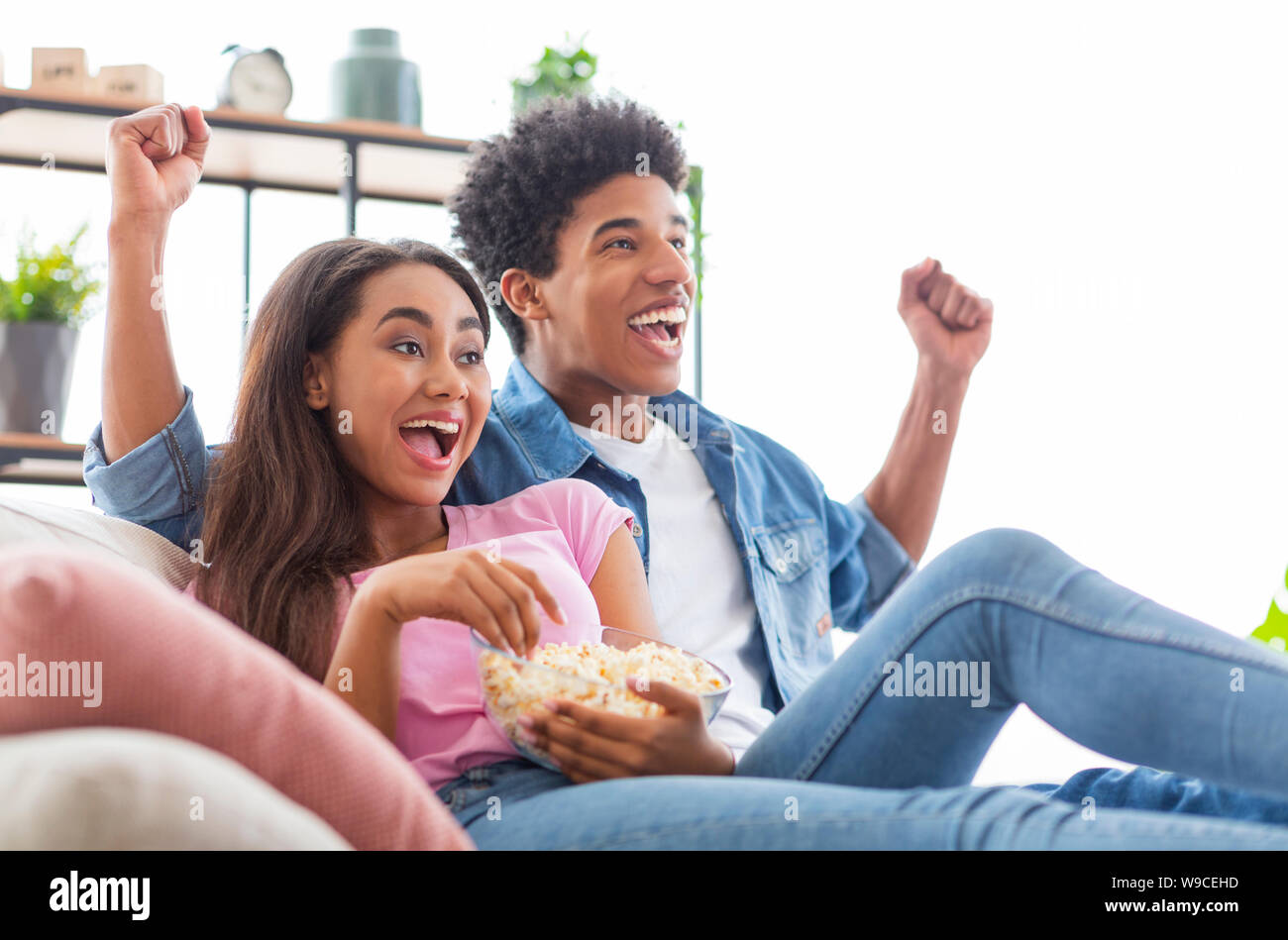 Schwarze teen Paar Fernsehen, sitzt mit Popcorn zu Hause Stockfoto