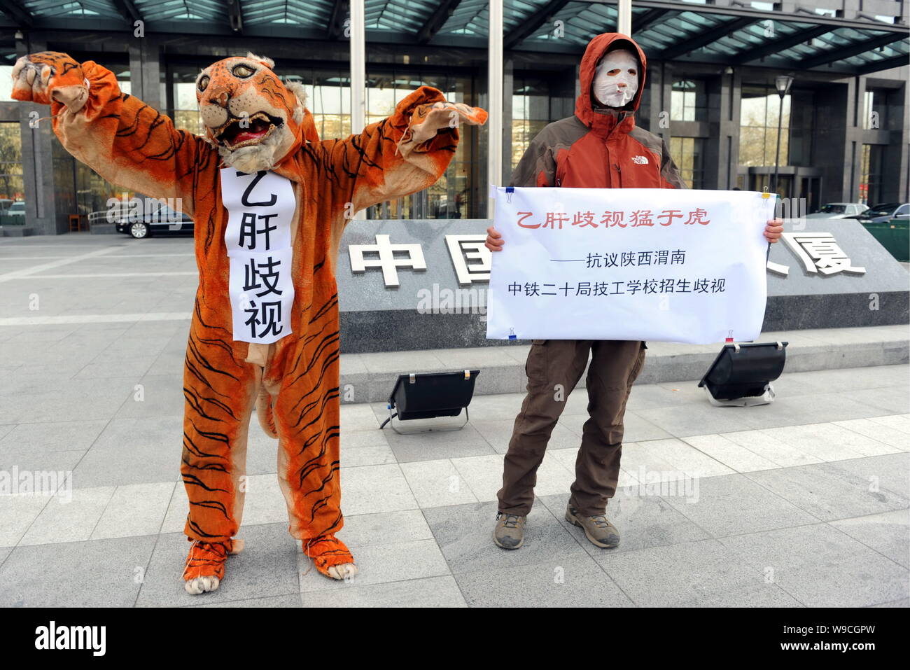Eine chinesische Menschenrechtsaktivist zeigt Anzeichen von Beschwerden neben einer Hepatitis Bvirus Träger wie ein Tiger in einem Protest gegen Diskriminierung gekleidet Stockfoto