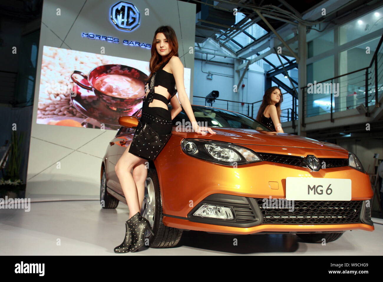 Modelle posieren mit einem MG 6, die von der SAIC Motor hergestellt, während ein in Shanghai, China, 10. Dezember 2009. Shanghai Automotive Industry Adr Stockfoto