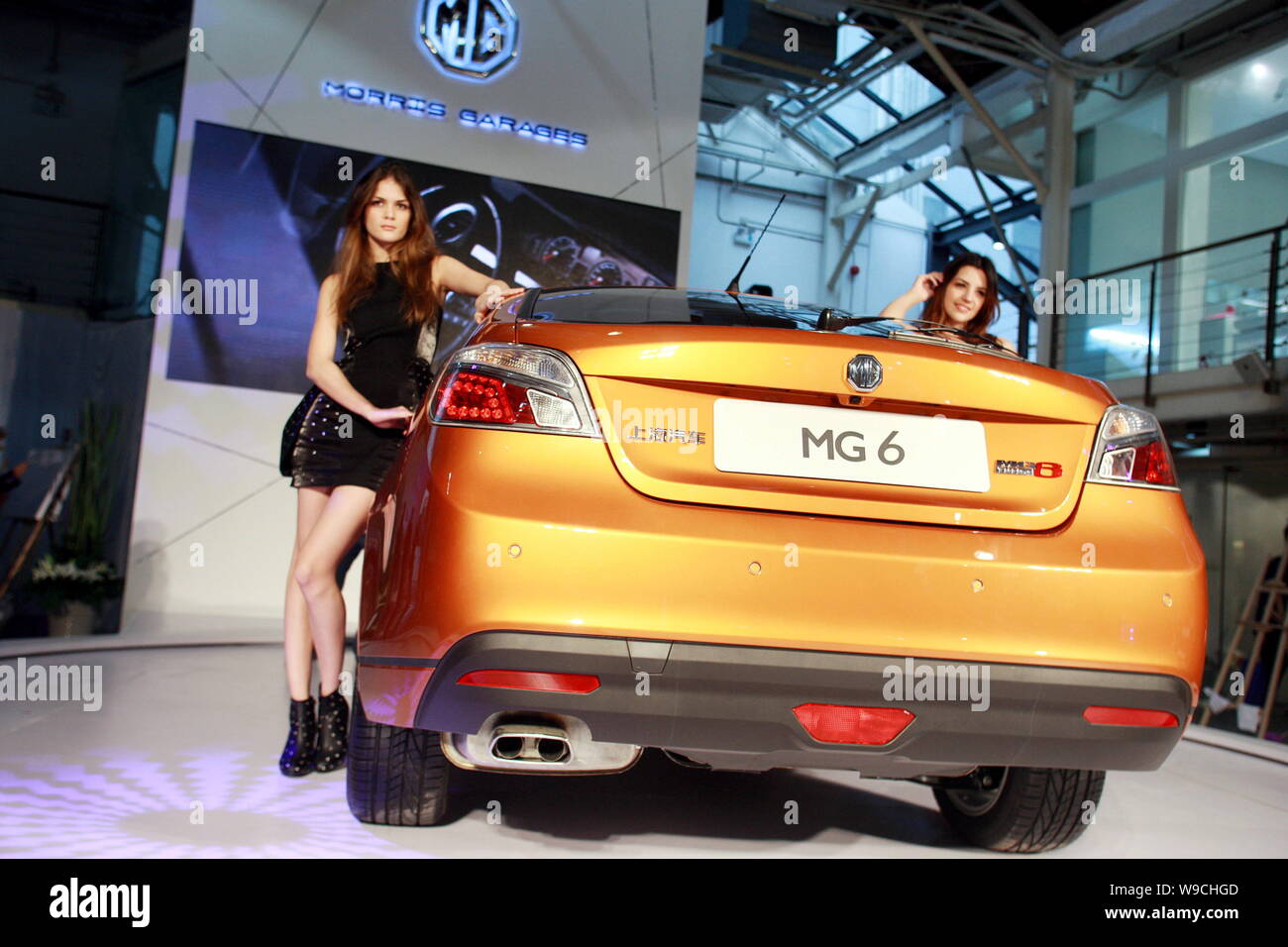 Modelle posieren mit einem MG 6, die von der SAIC Motor hergestellt, während ein in Shanghai, China, 10. Dezember 2009. Shanghai Automotive Industry Adr Stockfoto
