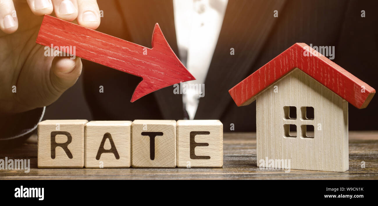 Unternehmer halten Sie die Nach-unten-Pfeil auf Holzklötze mit dem Wort- und Haus. Geringes Interesse an Hypotheken. Die Zinsen für die Hypothek. Stockfoto