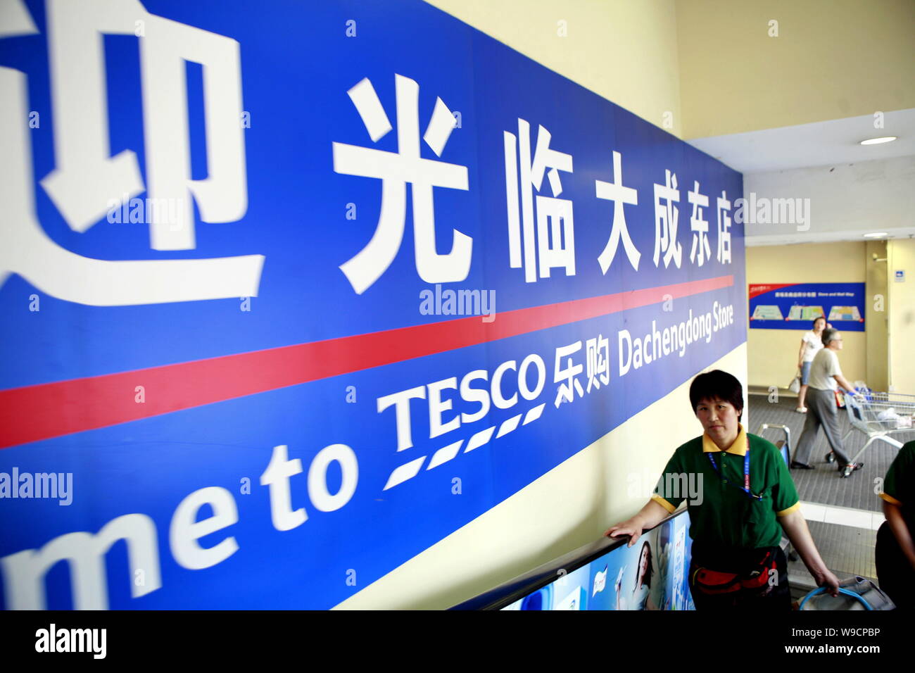 ------ Chinesische Kunden vorbei an einer Werbung für Tesco an einem Tesco Supermarkt in Peking, China, 23. August 2009. Tesco, Britains größte ret Stockfoto