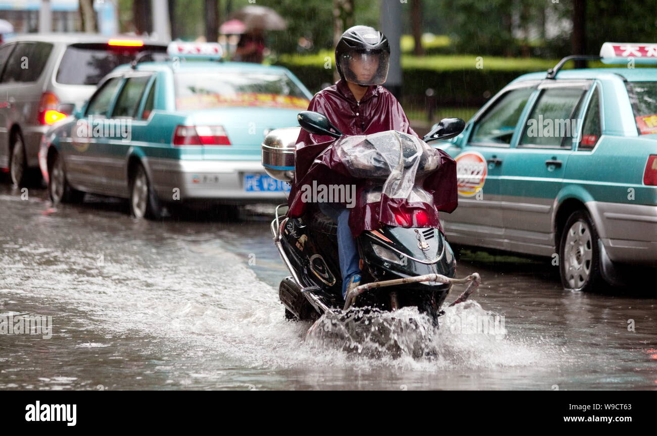Ein chinesischer Radfahrer und Autos durch eine Überflutete Straße nach starkem Regen in Shanghai, China, Donnerstag, 30. Juli 2009. Die schwersten Regenfälle seit 70 Jahren Stockfoto
