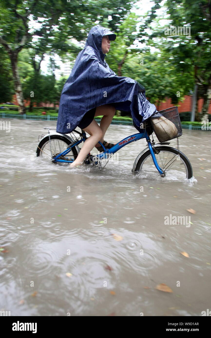 Ein chinesischer Radfahrer reitet ihr Fahrrad auf eine Überflutete Straße nach starkem Regen in Shanghai, China, Donnerstag, 30. Juli 2009. Die schwersten Regenfälle seit 70 Jahren Stockfoto