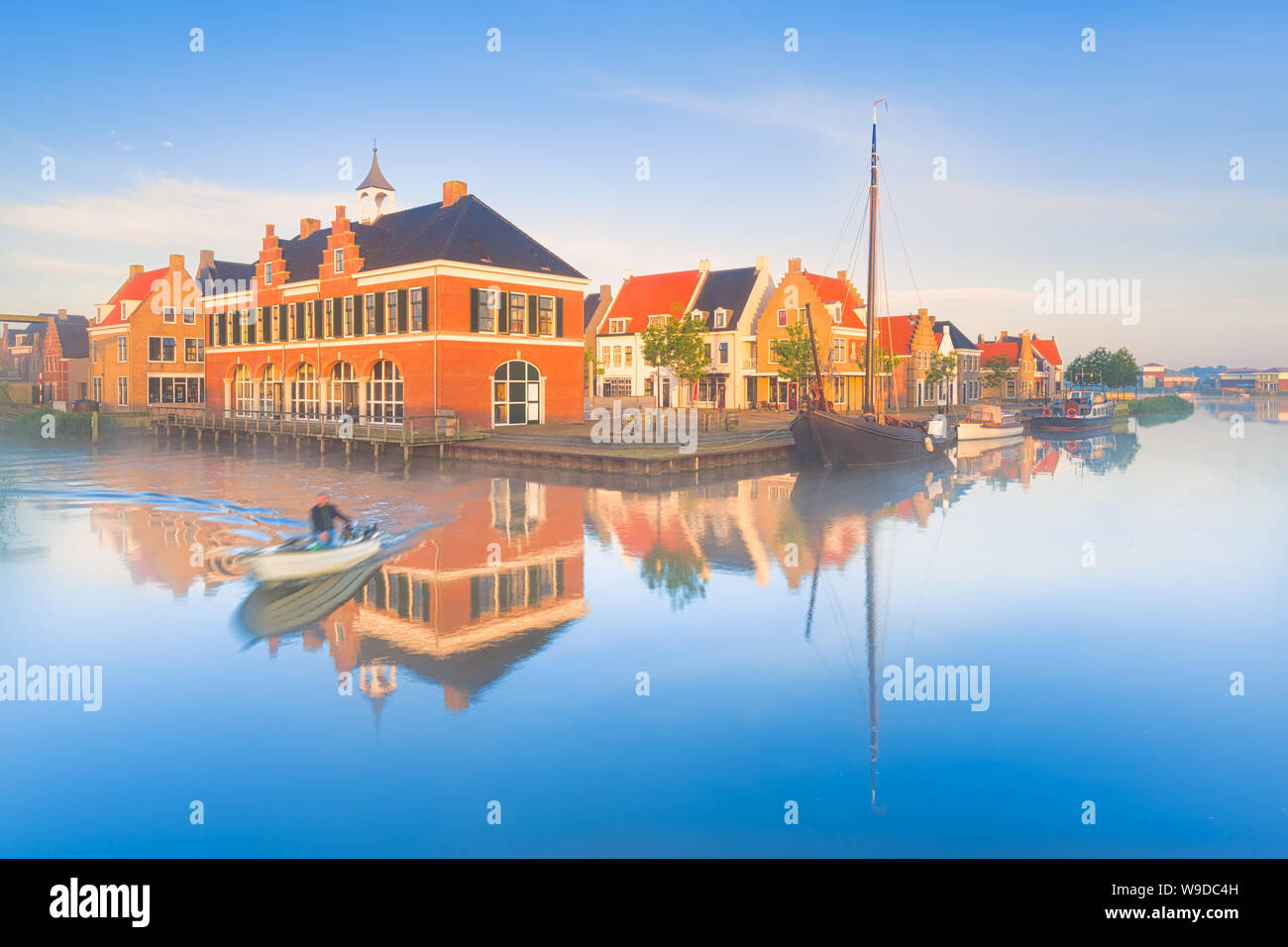 Traditionelle niederländische Häuser mit einem Kanal und Boote auf einem nebligen Pring morgen mit einem blauen Himmel und leuchtenden Farben - die Niederlande - Reise Bild Stockfoto