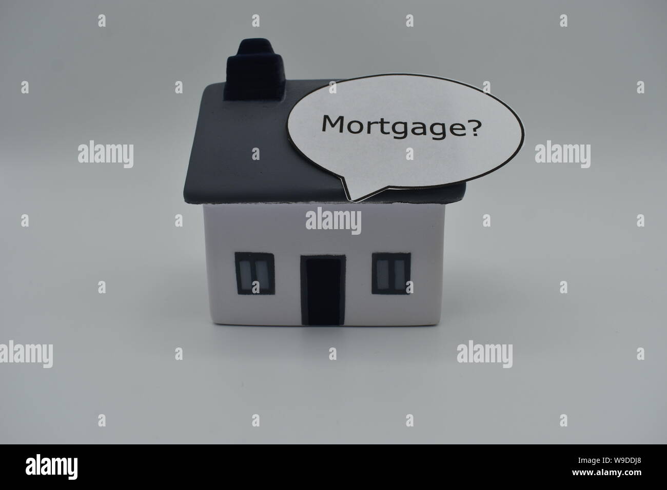 Ein Modell Haus mit dem Wort 'Durch Hypotheken?" in einer Sprechblase auf dem Dach. Stockfoto