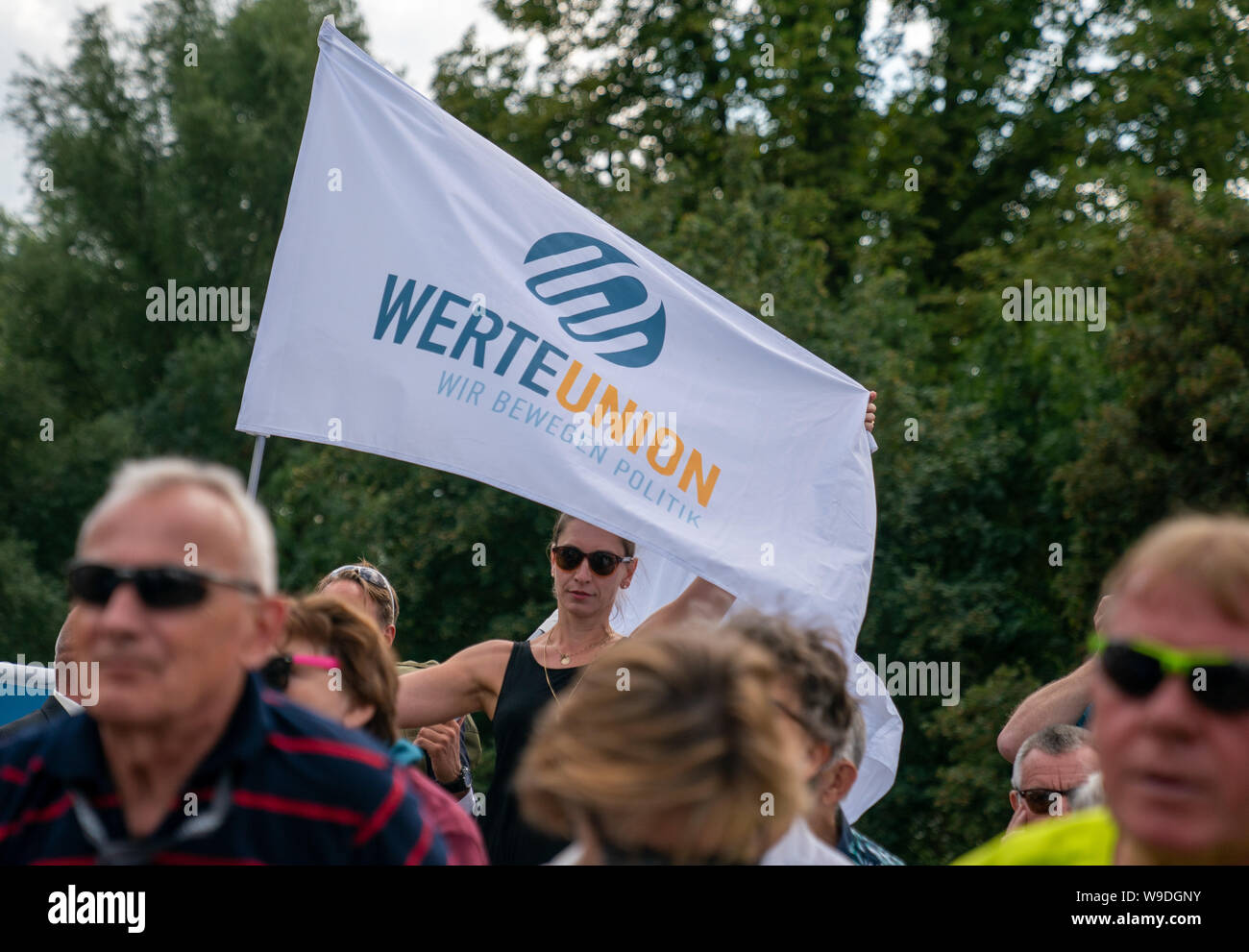 Potsdam, Deutschland. 13 Aug, 2019. Ein Verfechter der Werte der Union, ein konservativer Kreis von Mitgliedern der Union Parteien, Stände mit einer Flagge in einer Gedenkveranstaltung und Verlegung von einem Kranz an der Glienicker Brücke der Bau der Berliner Mauer vor 58 Jahren zu gedenken. Quelle: Michael Kappeler/dpa/Alamy leben Nachrichten Stockfoto