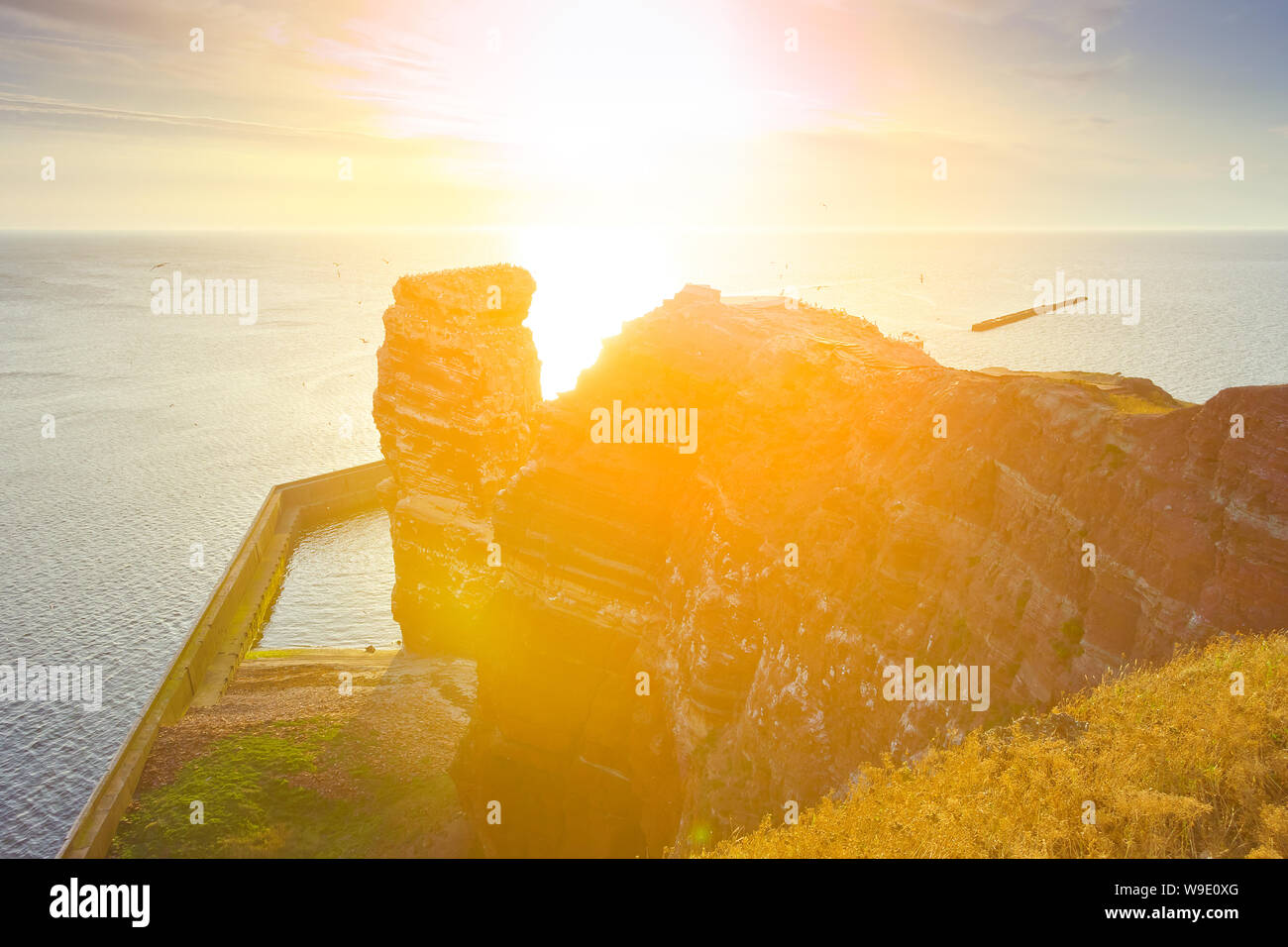 Die roten Sandsteinfelsen der deutschen Insel Helgoland mit der Formation "Lange Anna im warmen Abendlicht. Stockfoto