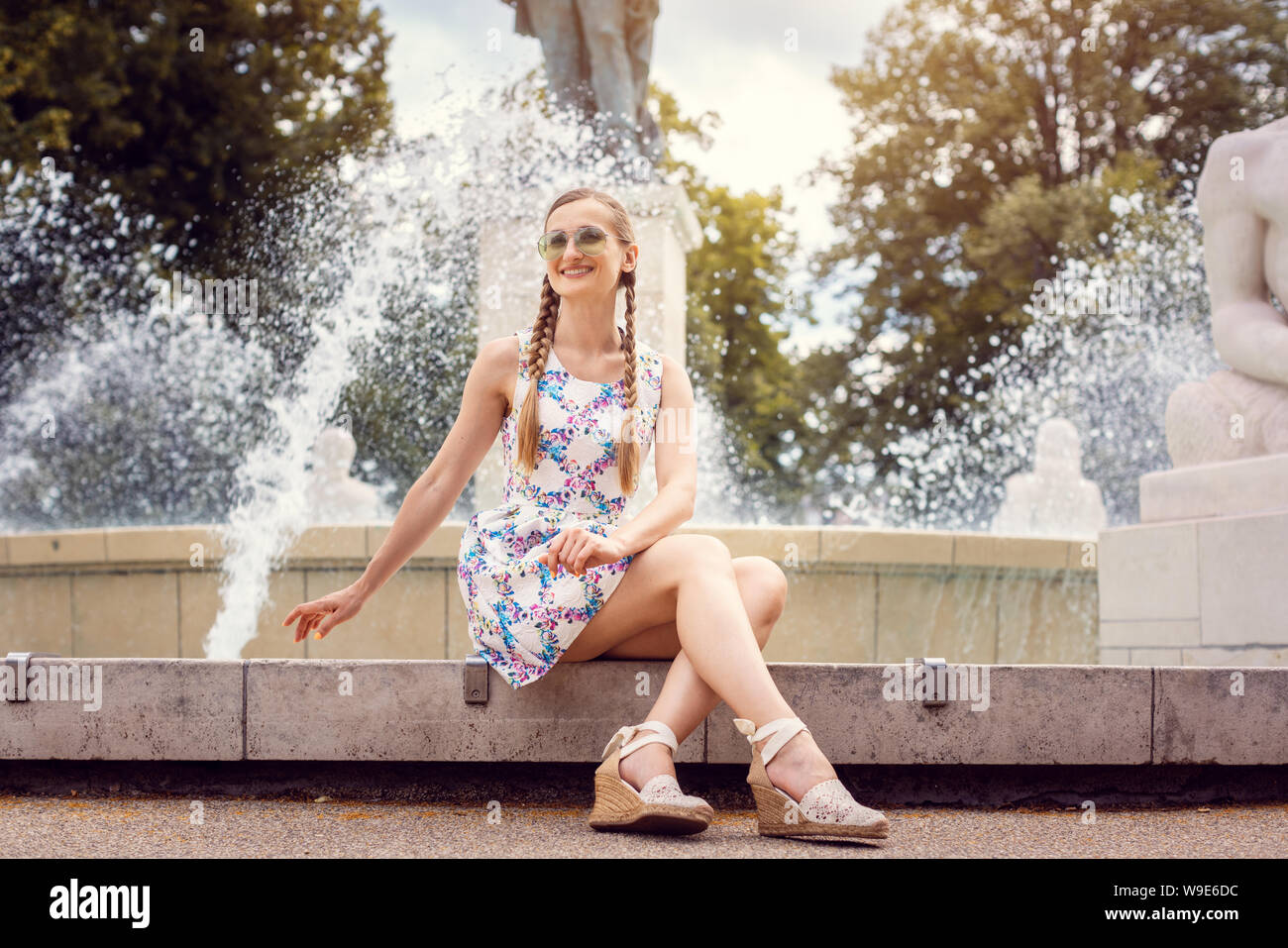 Frau sitzt am Rande eines Brunnens an einem heißen Sommertag Stockfoto
