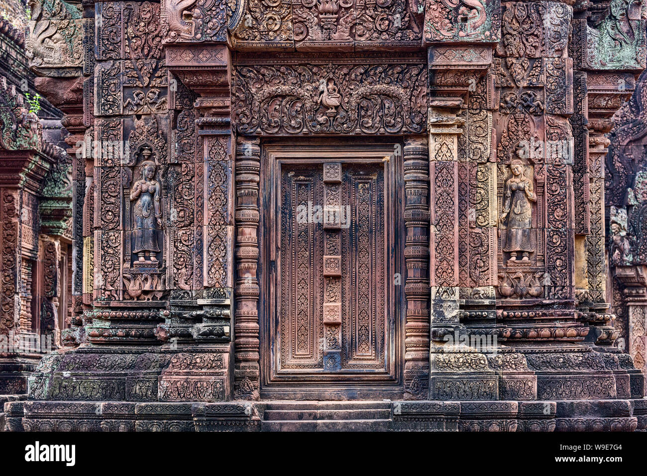 Blinde Tür, Geländerpfosten und Devatas geschnitzt in den roten Sandsteinmauern in Banteay Srei Tempel von Angkor in Siem Reap, Kambodscha Stockfoto