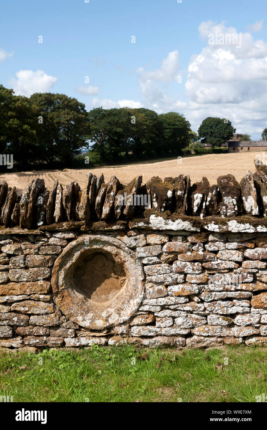 Eine alte Gedenkstein in der Wand von St. Mary's Friedhof, Warkworth, Northamptonshire, England, Großbritannien Stockfoto