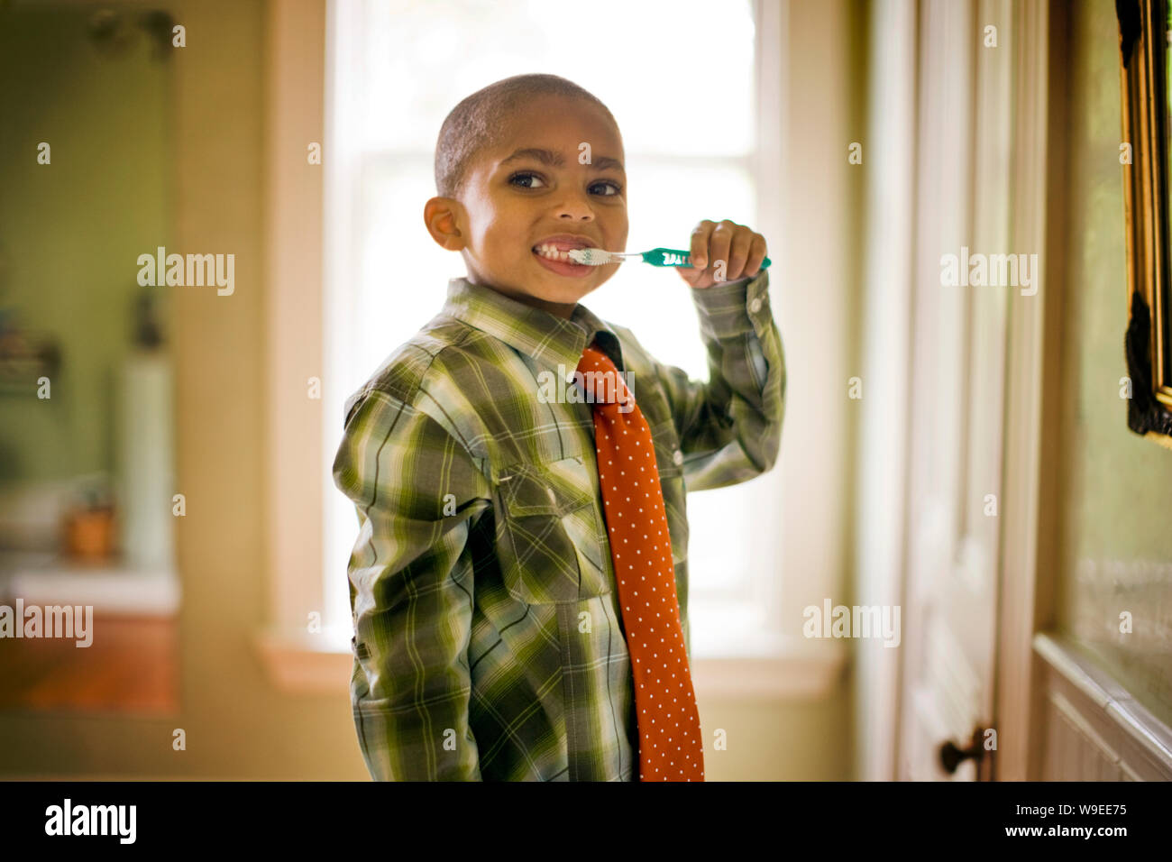 Junge in eine Krawatte Bürsten seine Zähne, wie er für ein Portrait Posen. Stockfoto
