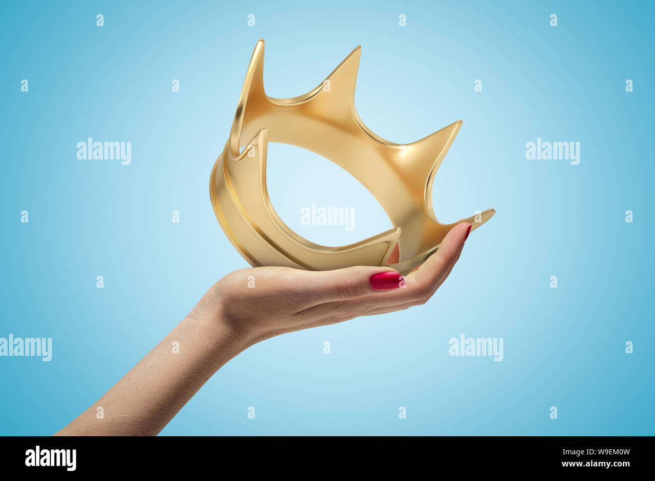 Weibliche Hand, die eine goldene Krone auf blauem Hintergrund Stockfoto