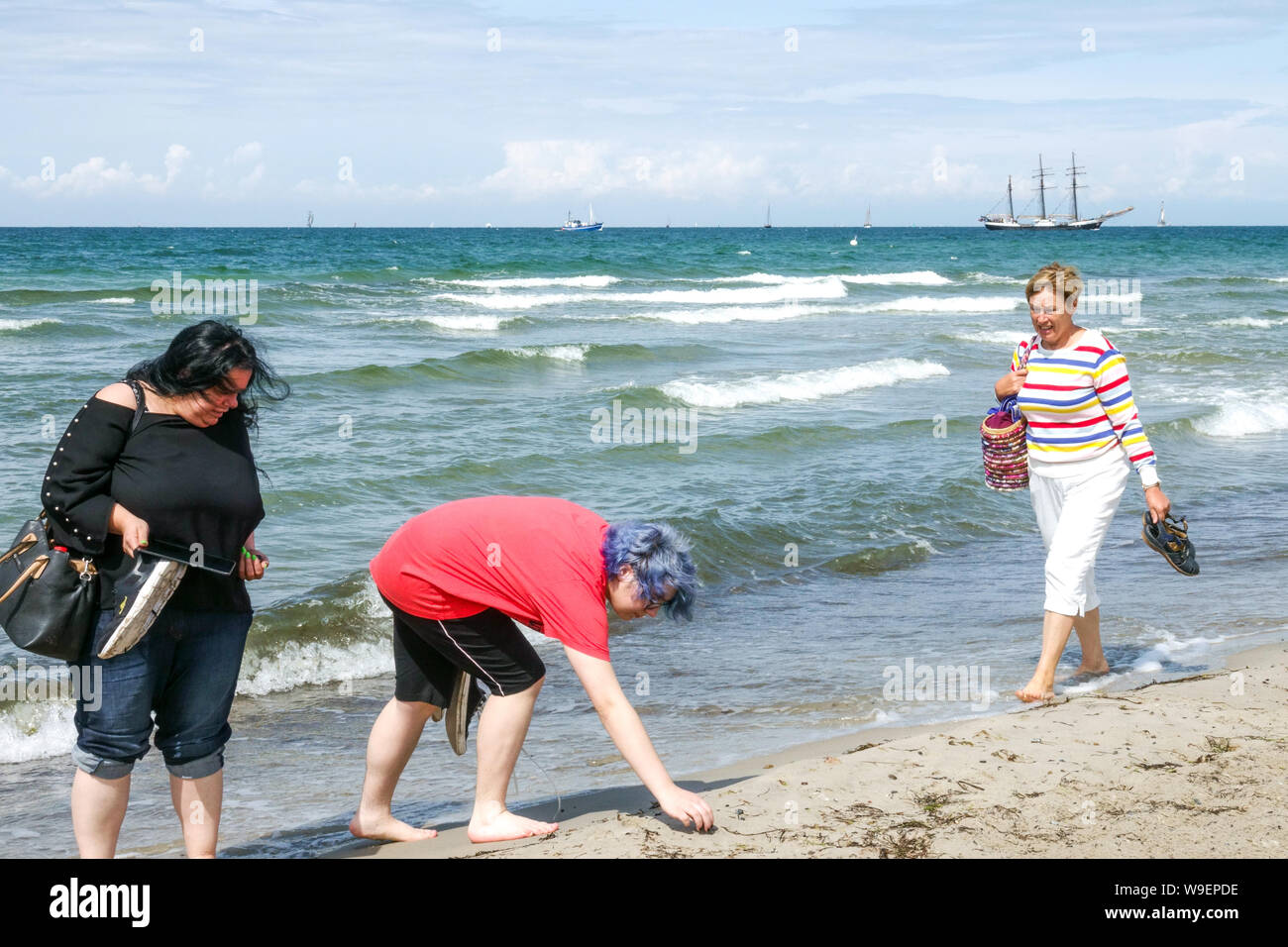 Drei Frauen Muscheln sammeln am Strand von Warnemünde Rostock Deutschland Stockfoto