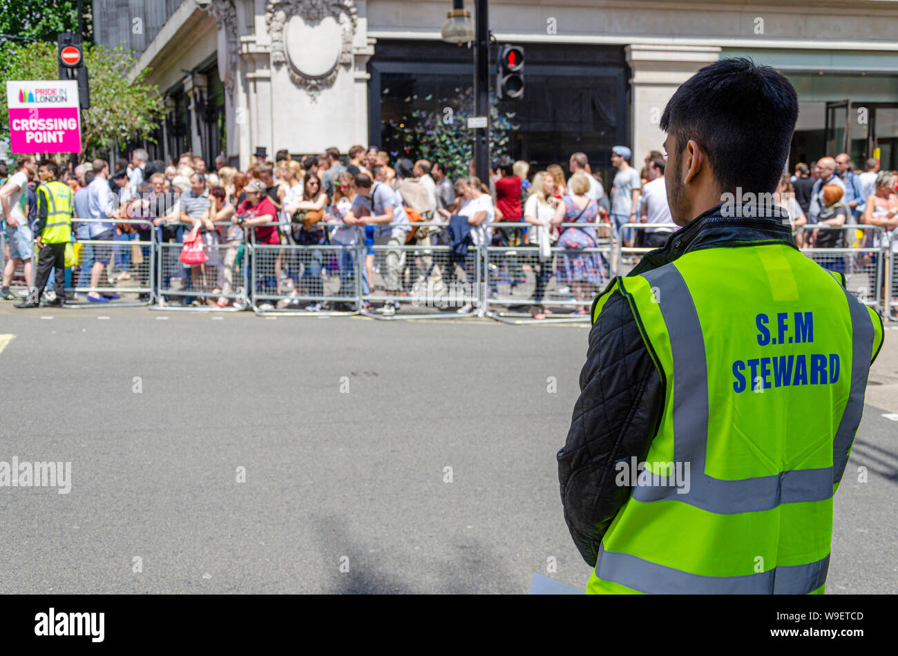 SFM Steward bei Pride in London beobachtet die Menge. Security Force Management Sicherheitsgeschäft. Kreuzungspunkt. Menschenmassen Stockfoto