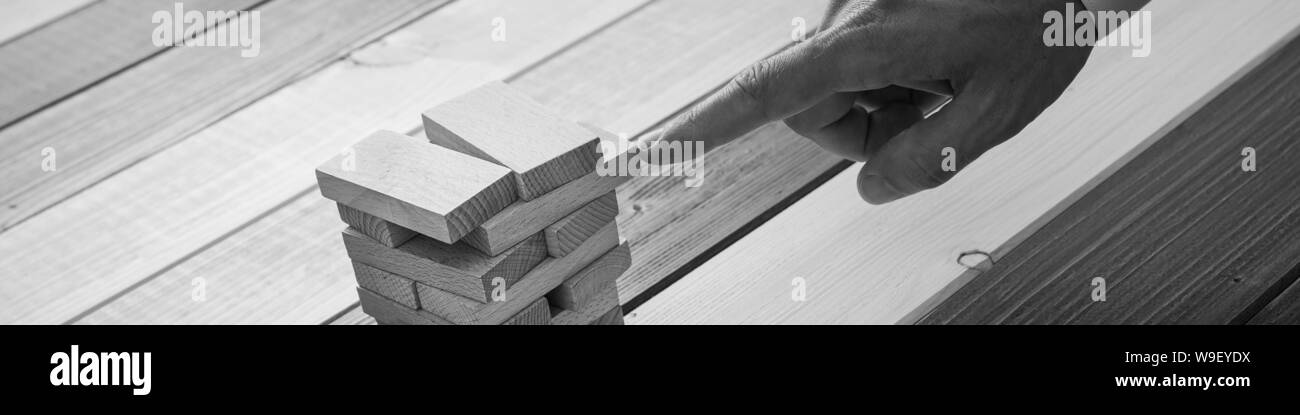 In der breiten Ansicht Bild der Geschäftsmann Schieben eines Holz- in einen Stapel von ihnen in einem konzeptionellen Bild der geschäftlichen Stabilität peg. Stockfoto