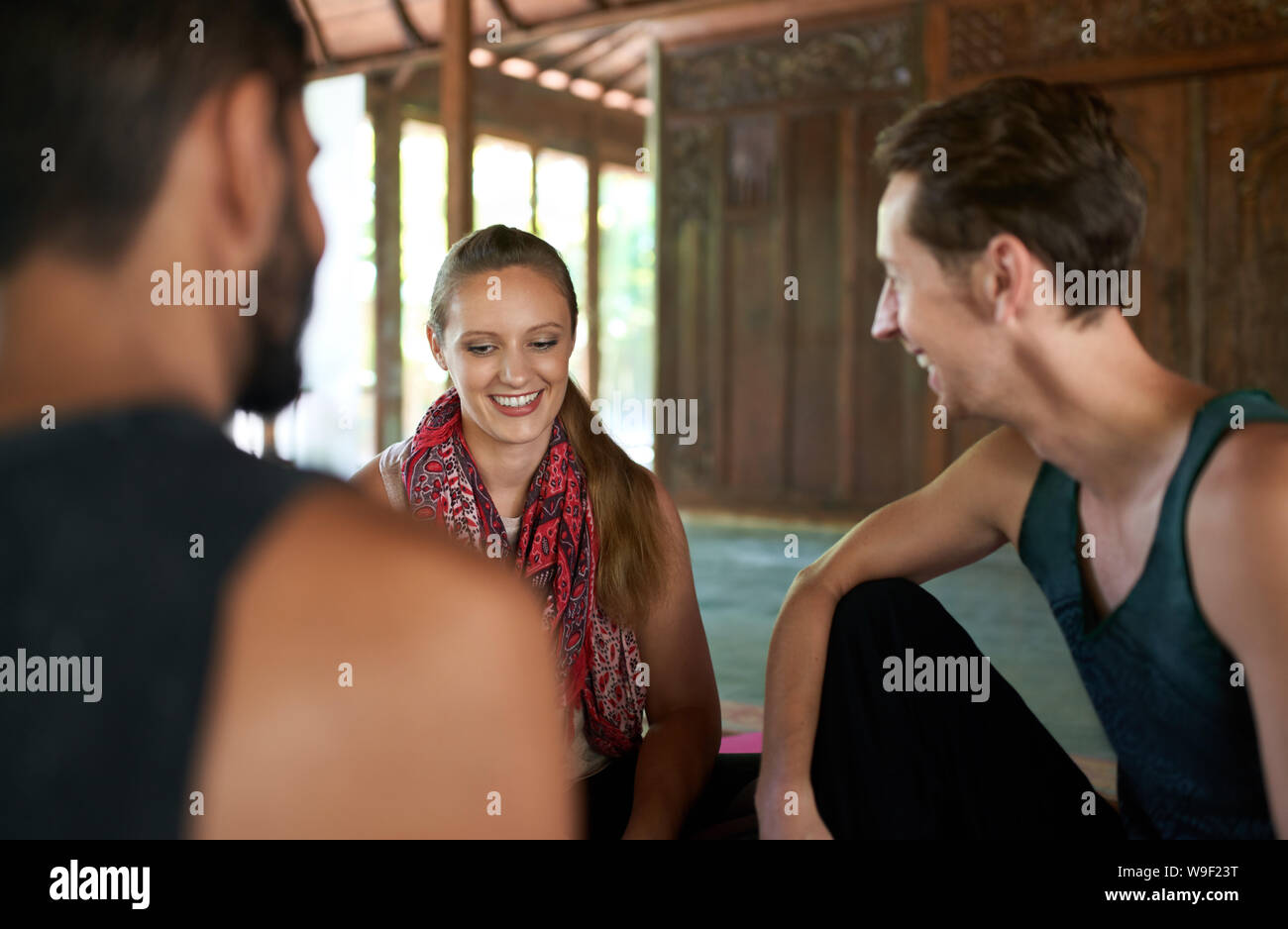 Candid shot von drei verschiedenen Freunden gemeinsam diskutieren nach Yoga Klasse in traditionellen Tempel auf Bali, Indonesien Stockfoto