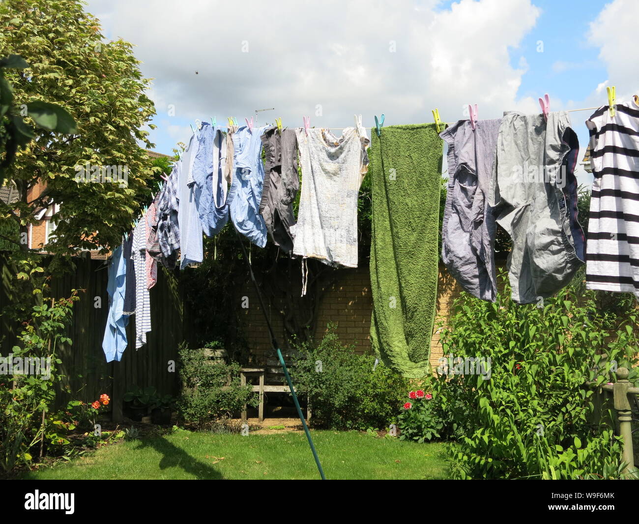 Ein Waschen der Kleidung hing mit Zapfen auf einer Wäscheleine in einem Englischen Garten zu trocknen. Stockfoto