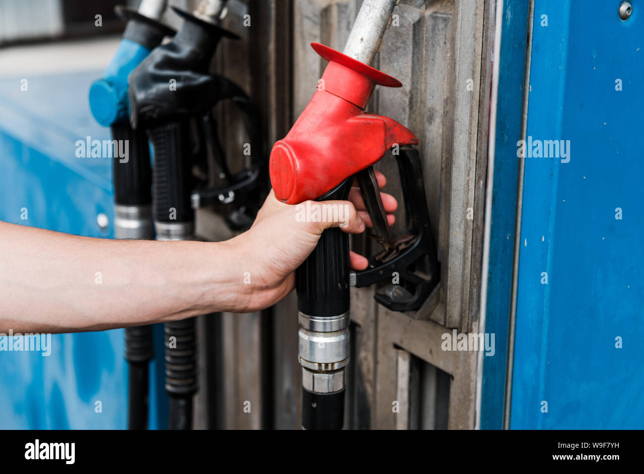 Selektiver Fokus der Mann hält rote Zapfsäule an der Tankstelle Stockfoto