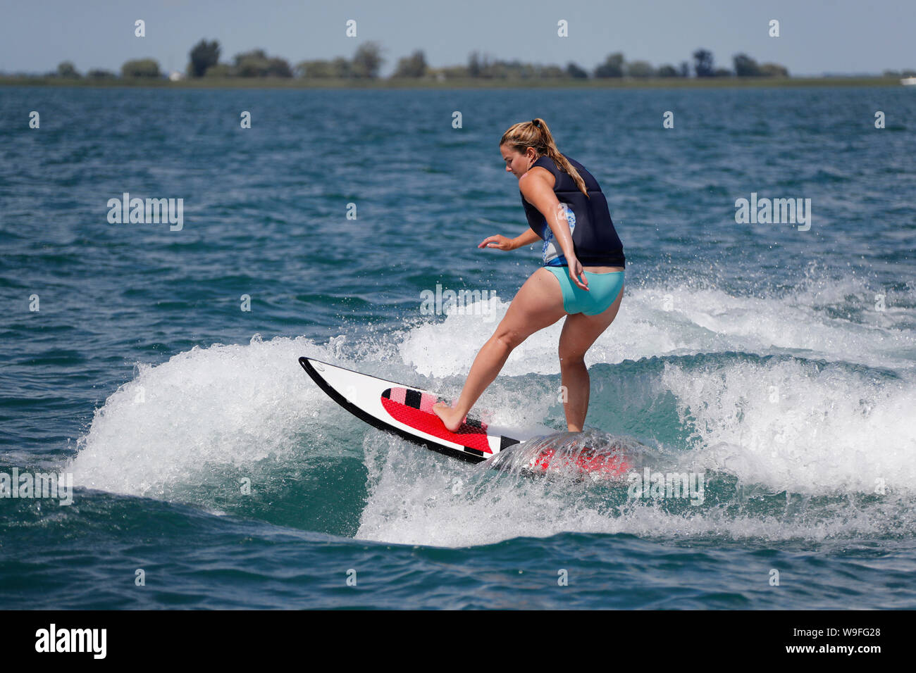 Eine Frau wakesurfing auf einem Boot. Stockfoto