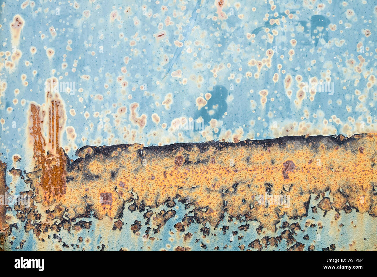 Ein texturaler Abstrakt aus Orangenrost auf blauem Metall. Stockfoto