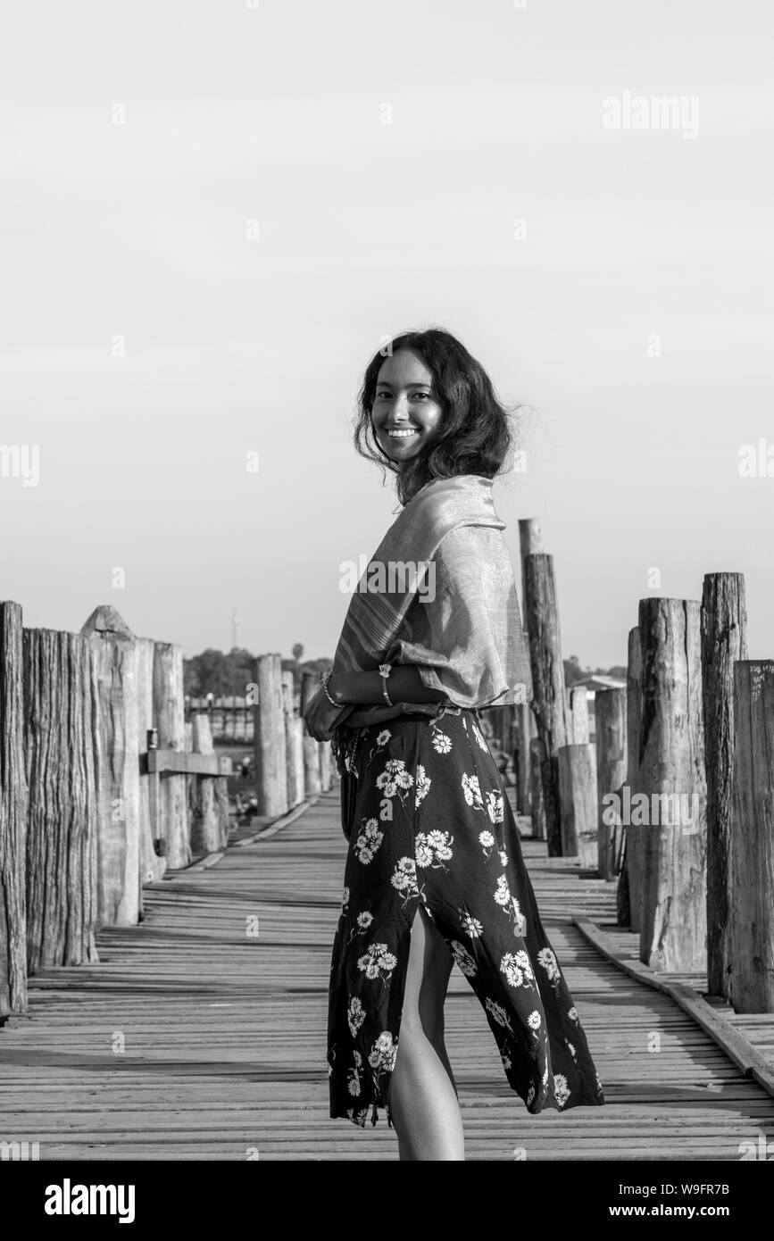 Schwarz-weiß Bild von Happy brunette Frau an Holz- U-Bein Brücke, die ist eine touristische Attraktion von Mandalay, Myanmar posing Stockfoto