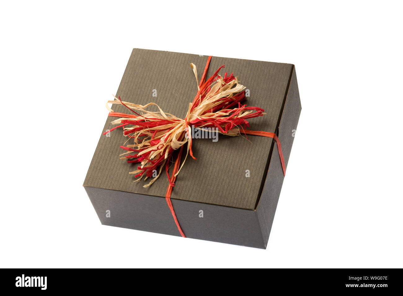 Schwarze Geschenkbox mit einem roten und tan natürliche Bastschleife auf einem weißen Hintergrund. Horizontale erschossen. Auf weiß isoliert. Stockfoto