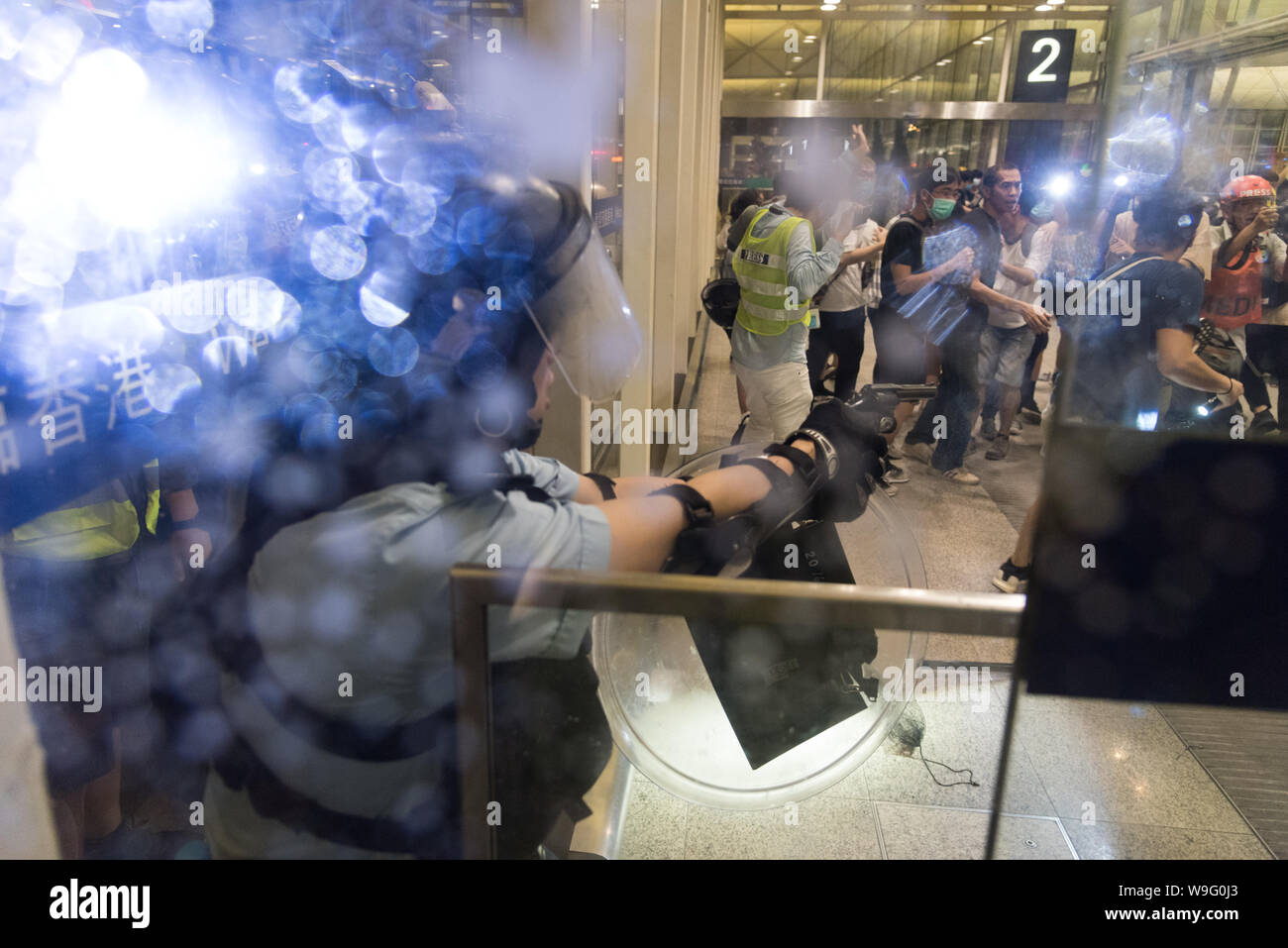 Ein Polizist soll seine Waffe gegen Demonstranten während der Demonstration. regierungsfeindlichen Demonstranten friedlich Sat-in am Internationalen Flughafen Hong Kong zum fünften aufeinander folgenden Tag bis später am Abend, wo verschiedene Ereignisse zu intensiven Konfrontation und Gewalt mit der Polizei geführt. Die Sit-in zu massenhaften Flugausfälle geführt und soll das Bewusstsein der Demonstranten "Kampf gegen die Auslieferung Rechnung zu erhöhen und die Brutalität der Polizei zu protestieren. Stockfoto