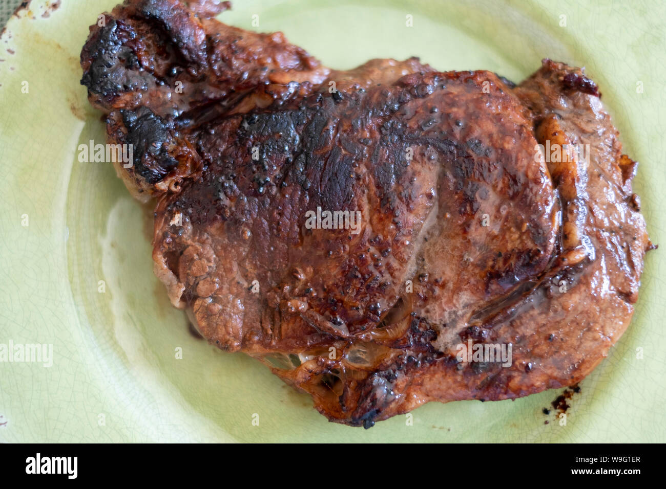 Nahaufnahme eines Gegrilltes ribeye Steak, Medium, in einer grünen Platte serviert. Stockfoto