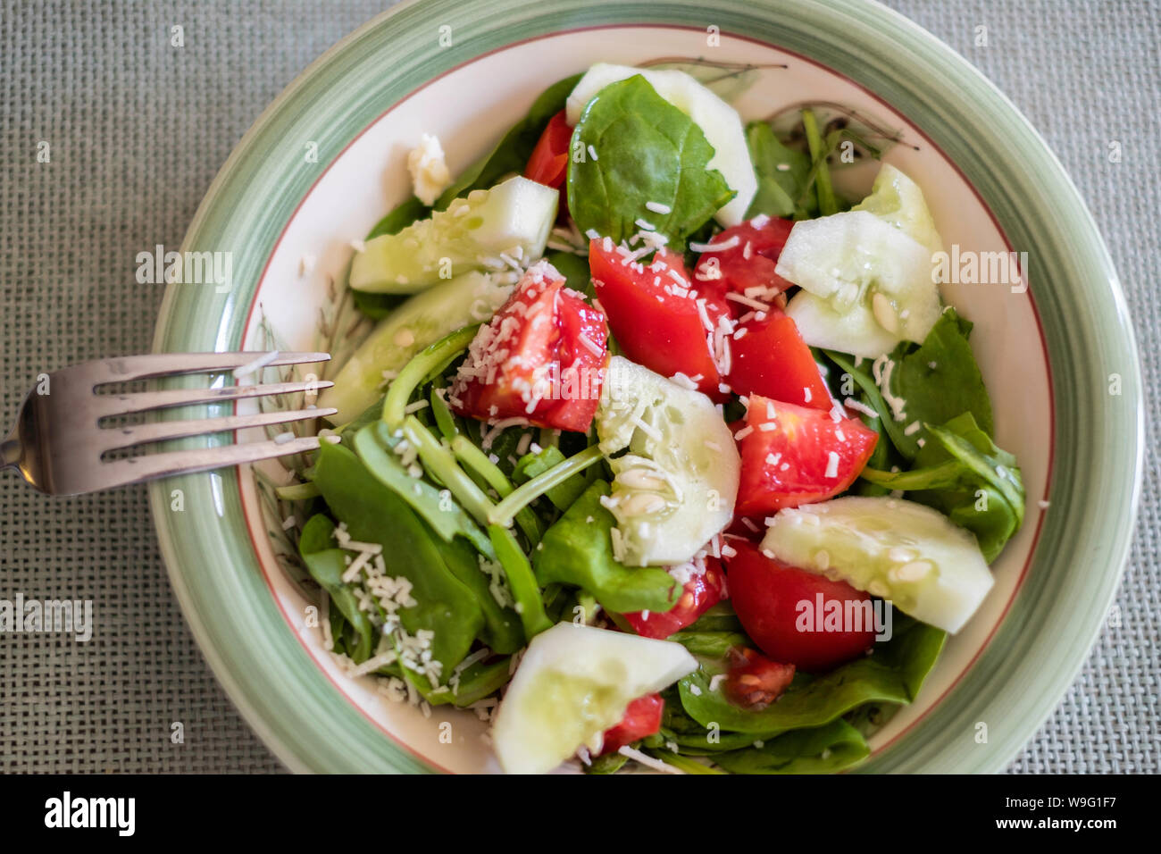 Frischer Spinat, Gurken und Tomaten Salat garniert mit geriebenem Parmesan. Stockfoto