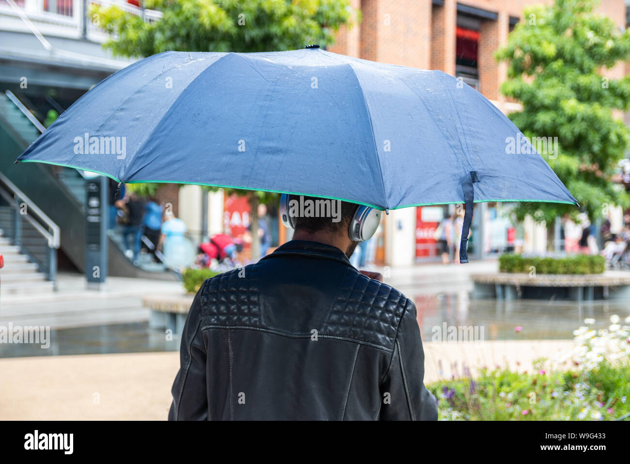 Ein Mann auf der Suche nach Unterschlupf vor dem Regen, während Sie einkaufen Stockfoto