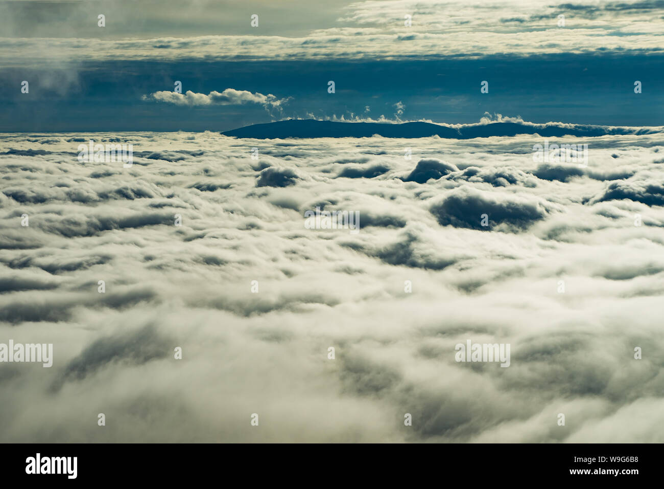Die hohen Berge, die durch einen Schleier von Wolken bedeckt. Über den Wolken. Stockfoto